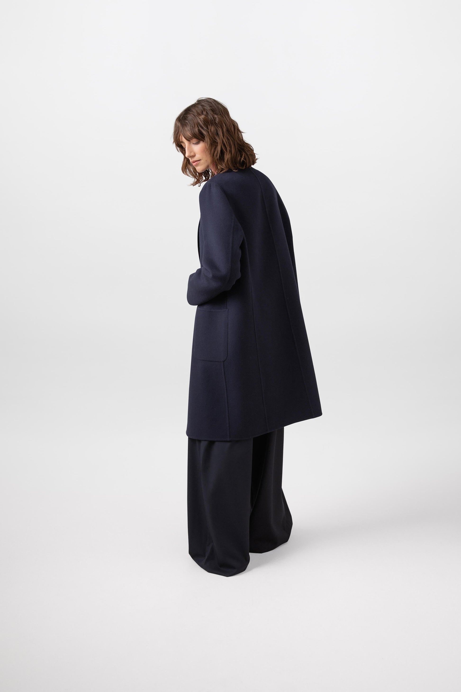 Johnstons of Elgin Women's Cashmere Crombie Coat in Navy worn with a Sea Pink Merino Roll Neck on a white background TA000520RU7291
