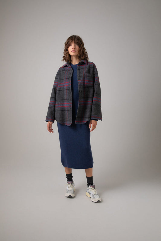 Johnstons of Elgin Women's Wool Blend Oversized Shirt in Charcoal Check worn with a Navy Cashmere Sweater & Skirt on a grey background TB000630RU7387