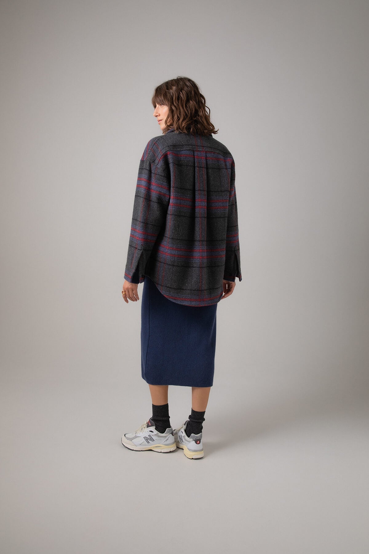 Back of Johnstons of Elgin Women's Wool Blend Oversized Shirt in Charcoal Check worn with a Navy Cashmere Sweater & Skirt on a grey background TB000630RU7387