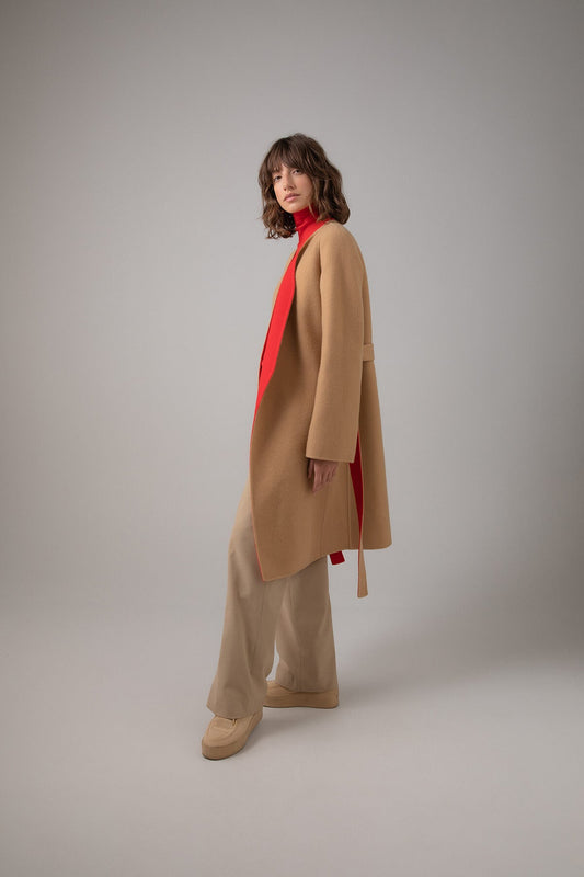 Side of Johnstons of Elgin Women's Collarless Cape Wool Blend Coat in Camel & Red worn with a matching Roll Neck Sweater and Camel Trousers on a grey background TB000633RU7380