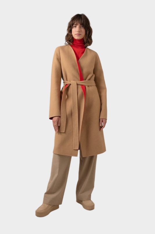 Johnstons of Elgin Women's Collarless Cape Wool Blend Coat in Camel & Red worn with a matching Roll Neck Sweater and Camel Trousers on a grey background TB000633RU7380