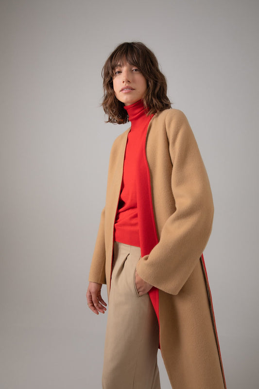 Model wearing Johnstons of Elgin Women's Collarless Cape Wool Blend Coat in Camel & Red worn with a matching Roll Neck Sweater and Camel Trousers on a grey background TB000633RU7380