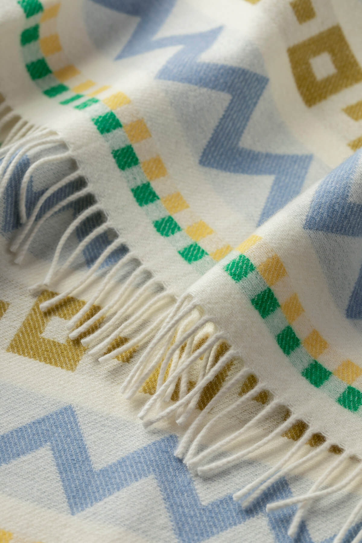 Detail of a Johnstons of Elgin Children's Zig Zag Blanket in shades of blue, green, and cream on white background WB002334RU7276ONE