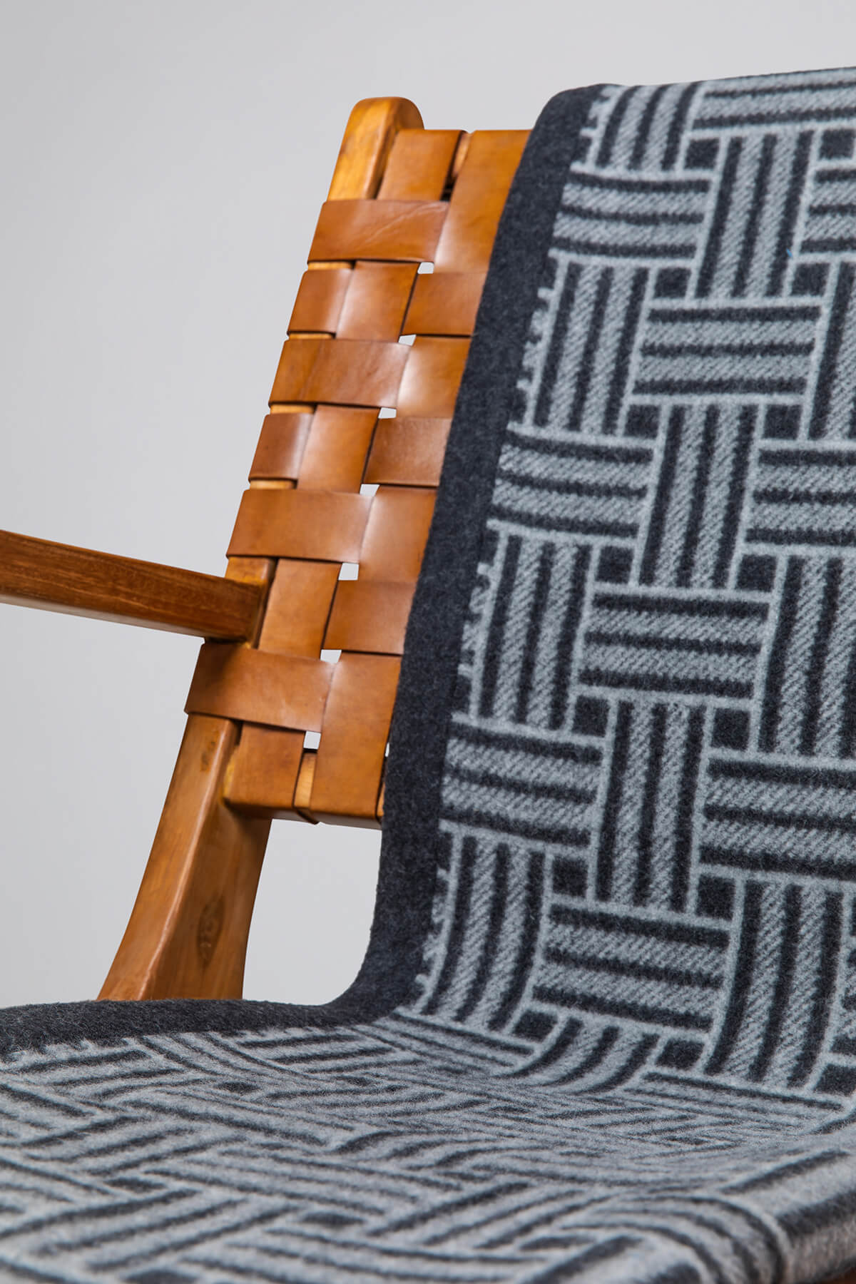 Johnstons of Elgin’s Charcoal & Grey Basket Weave Throw on brown chair on a grey background TB000470RU6998ONE