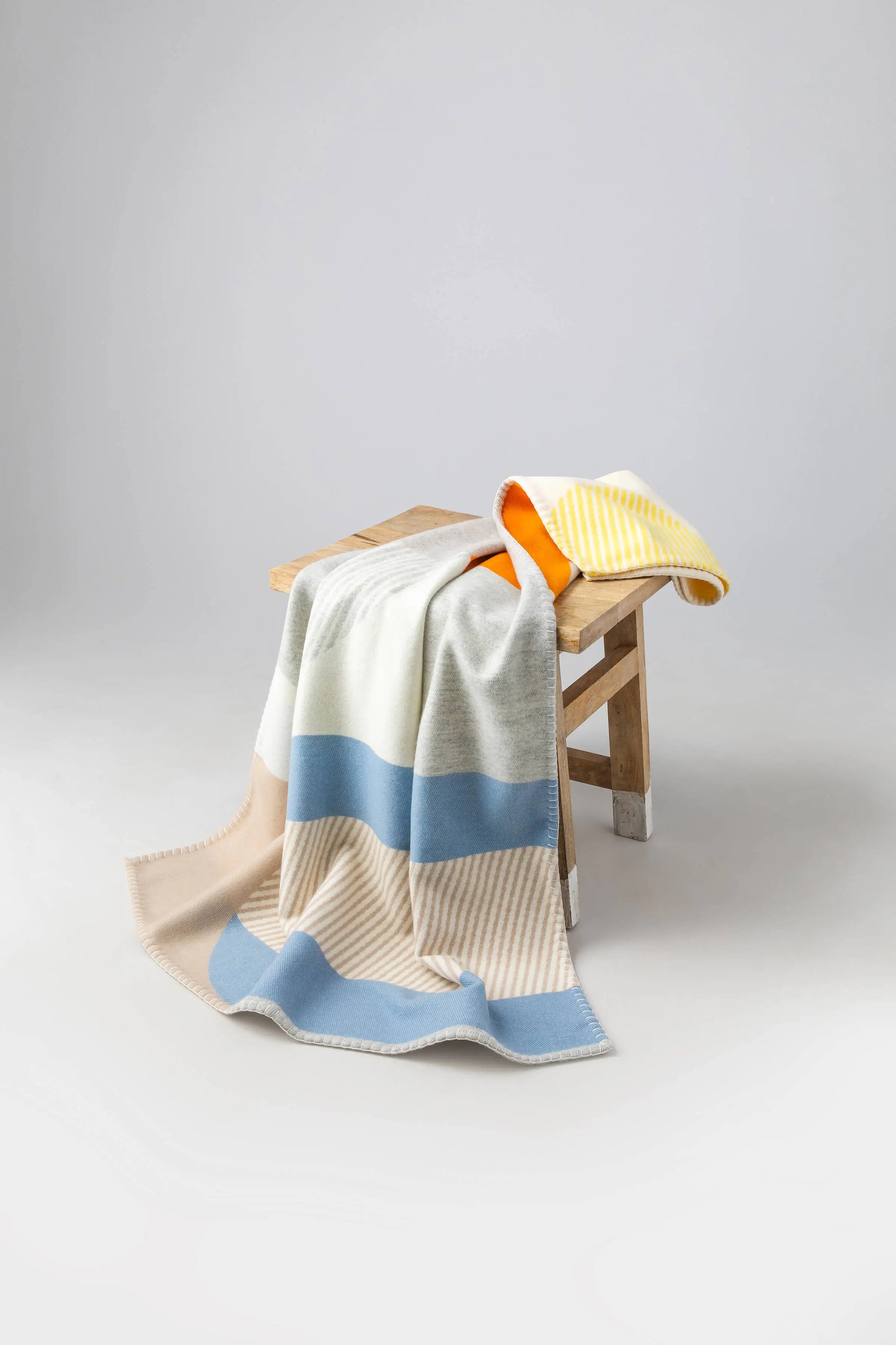 2025 Johnstons of Elgin Interiors Collection  Playful Shapes' Children's Blanket on a wooden stool on a  grey background  TB000582RU7440ONE