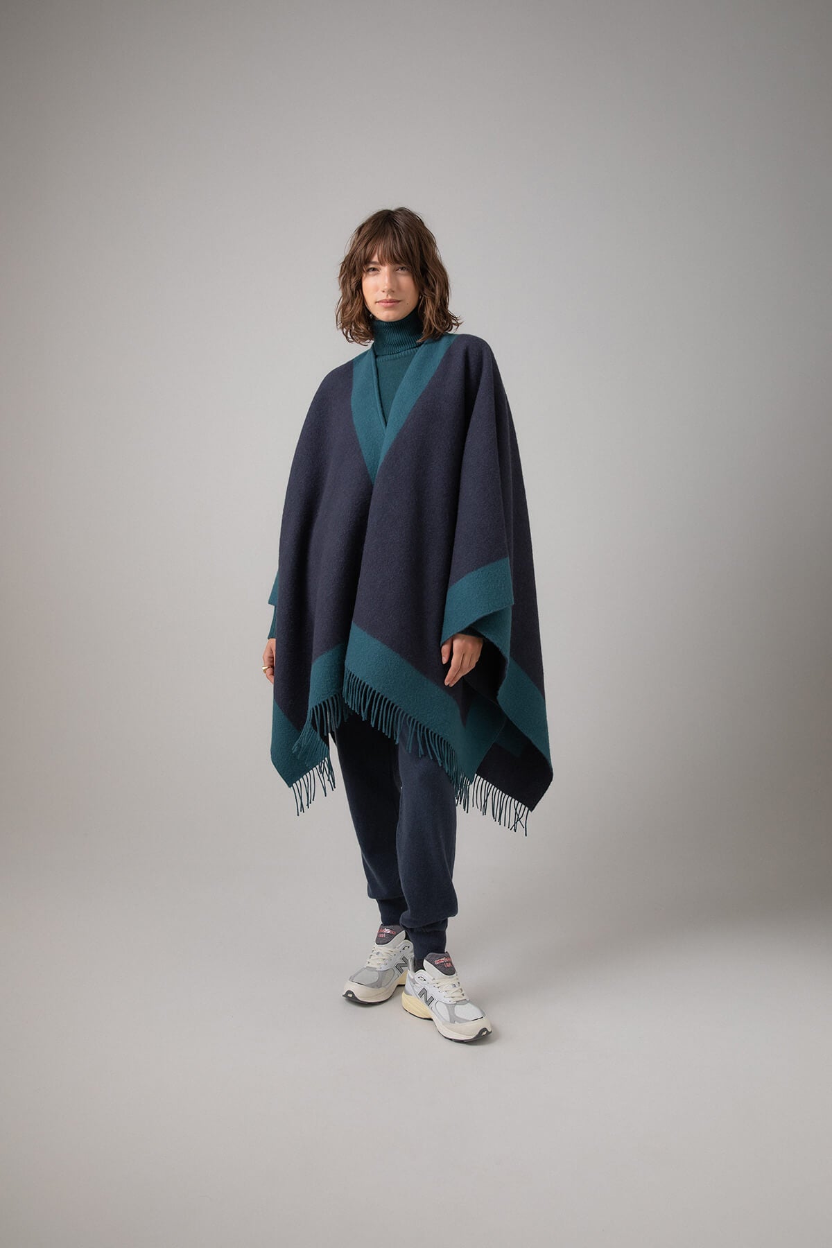 Johnstons of Elgin Merino Wool Cape with Contrast Border in Mallard worn matching sweater and Mazarine Joggers on a grey background TD000230RU7358ONE