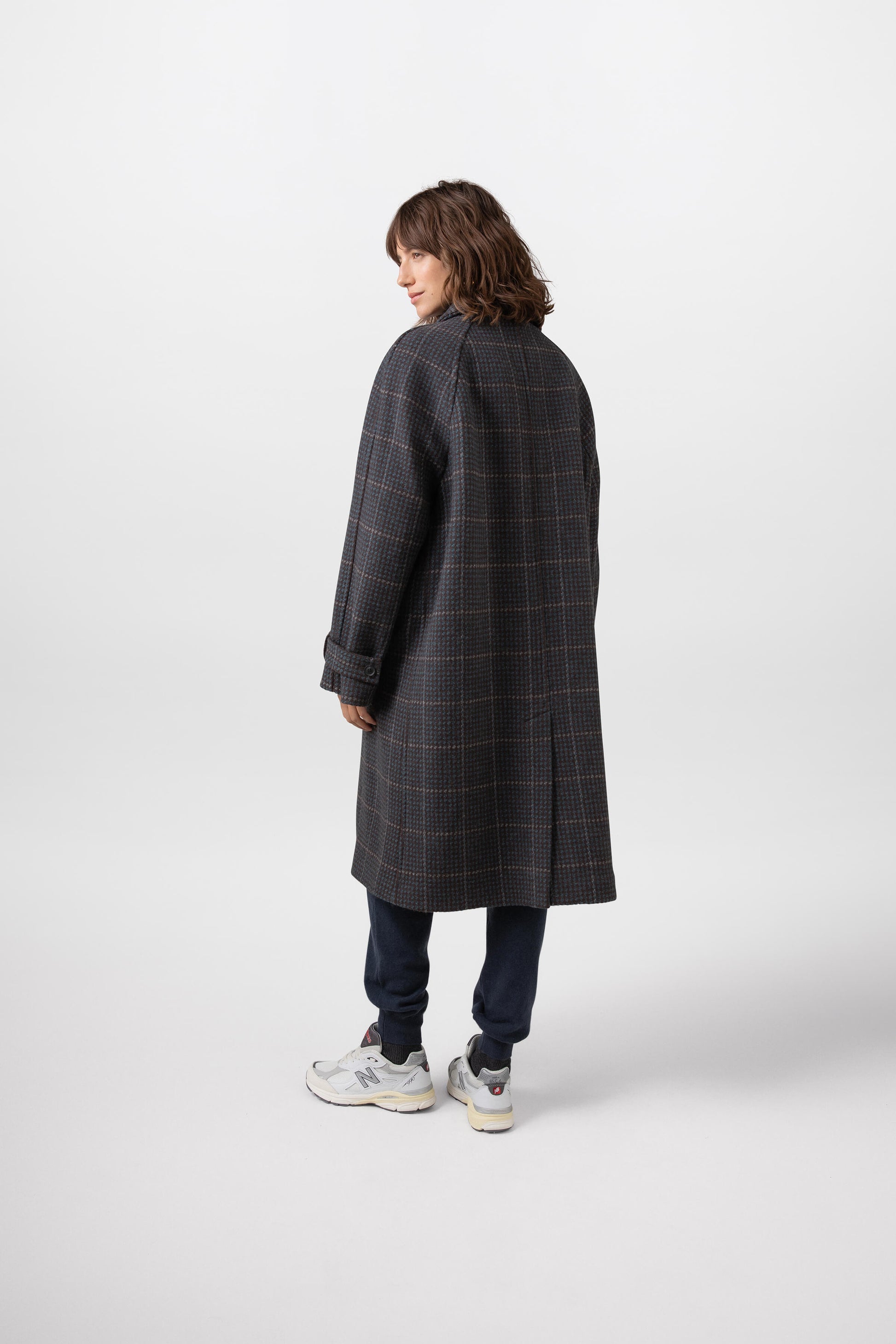 Model wearing Johnstons of Elgin Women's Balmacaan Coat in Peat Hairline worn over a Mallard Cashmere Sweater on a grey background TD000417RU7378