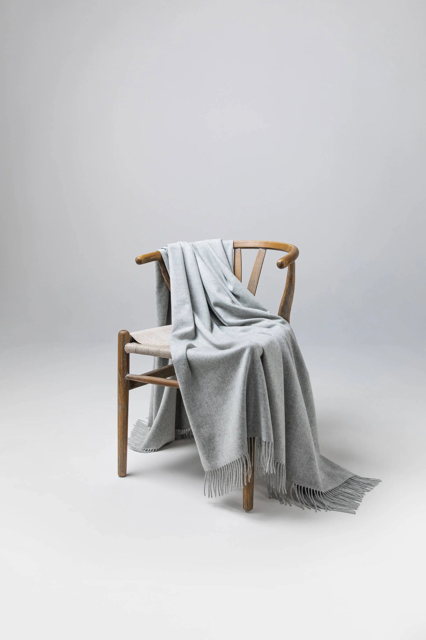 2025 Johnstons of Elgin Interiors Collection  Silver Cashmere Throw on a wooden chair background  WA000055HA0100ONE