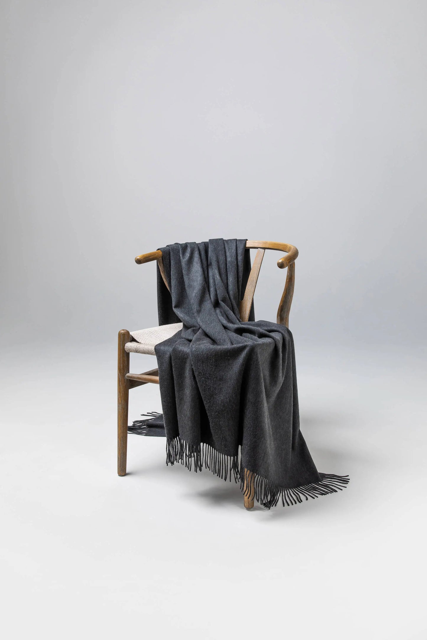 2025 Johnstons of Elgin Interiors Collection  Charcoal Cashmere Throw on a wooden chair WA000055HA0700ONE