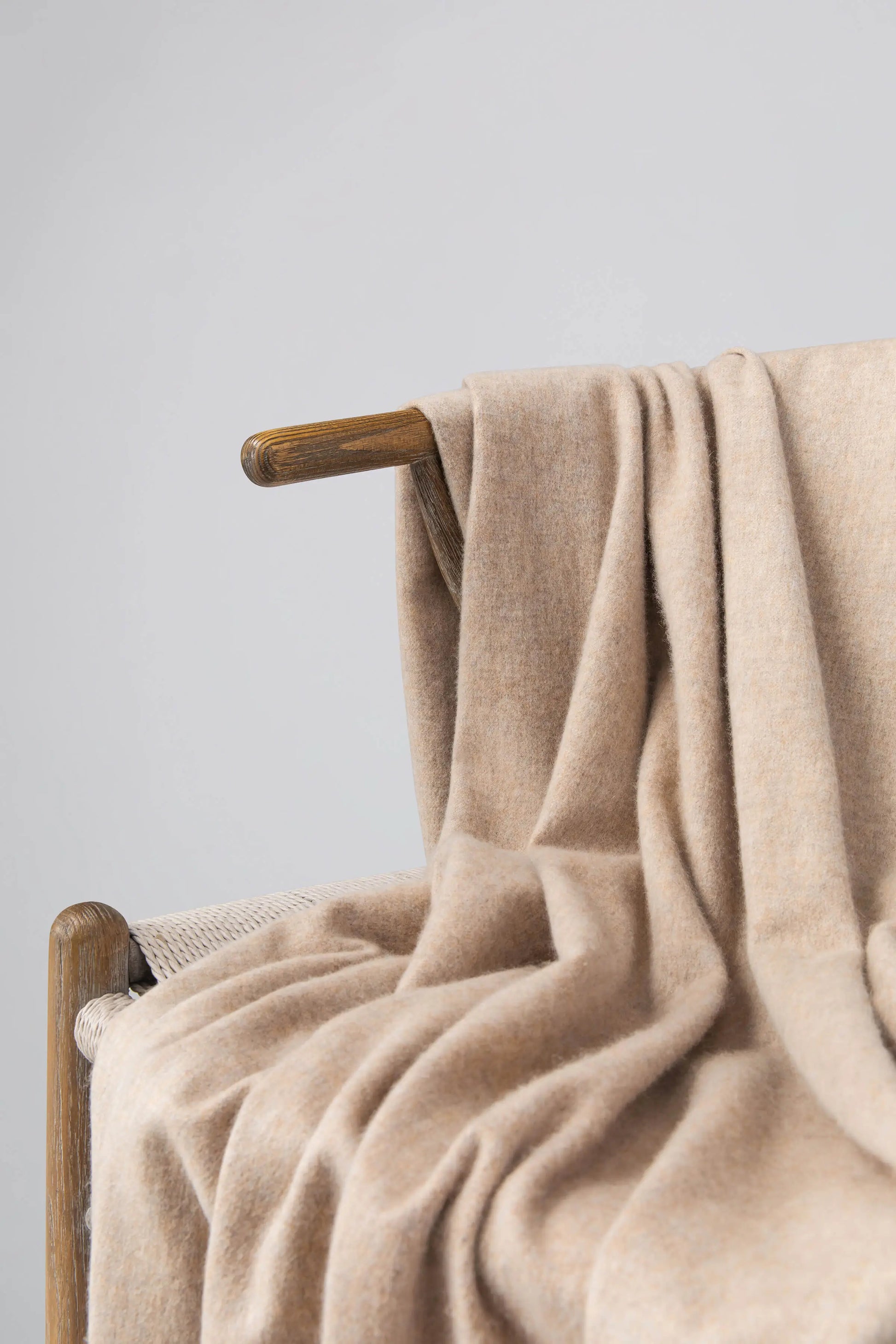 2025 Johnstons of Elgin Interiors Collection Oatmeal Cashmere Throw on a wooden chair WA000055HB0210ONE