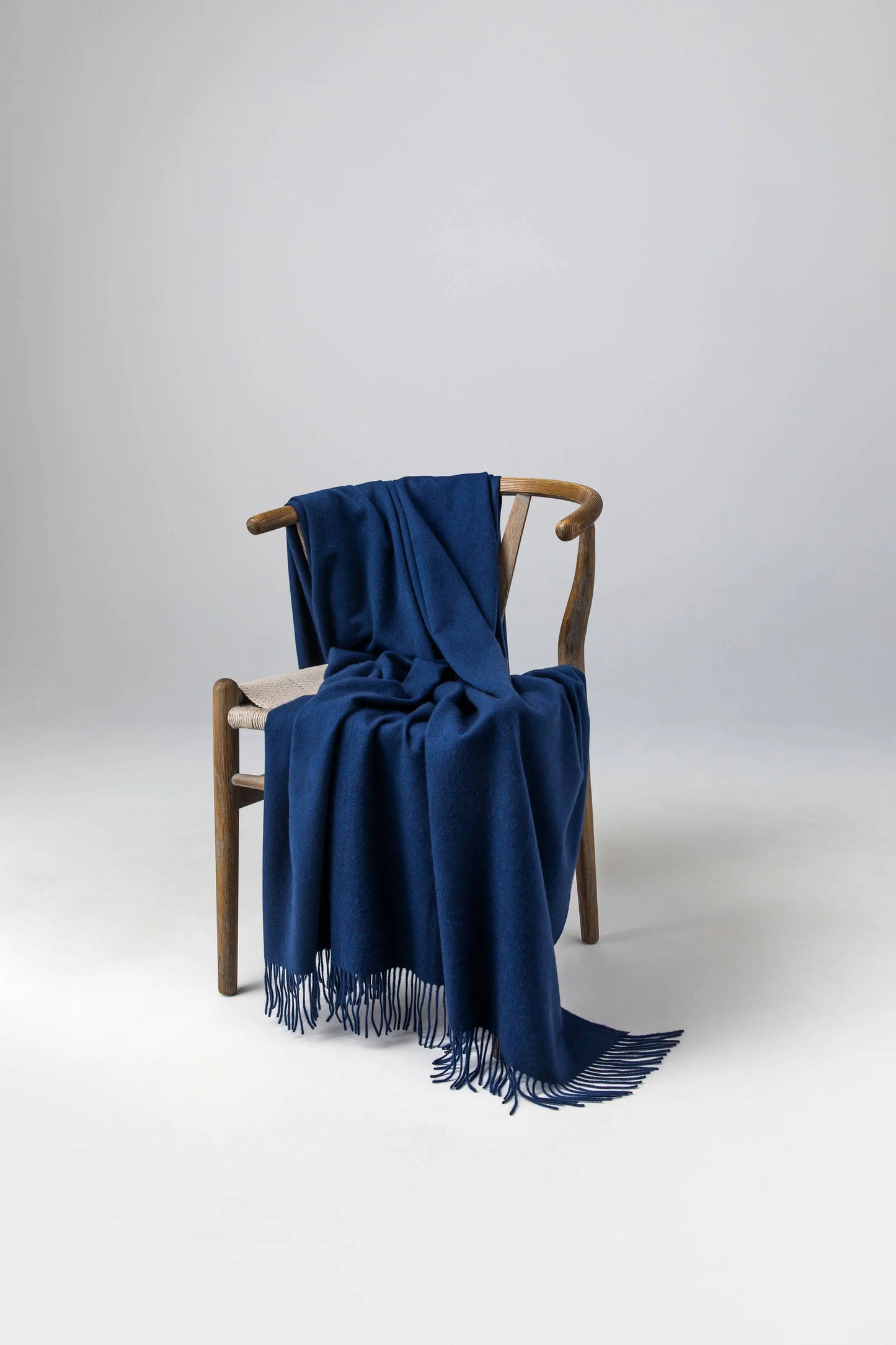 Johnstons of Elgin 2024 Blanket Collection Ocean Plain Cashmere Throw on a wooden chair  WA000055HD7244ONE