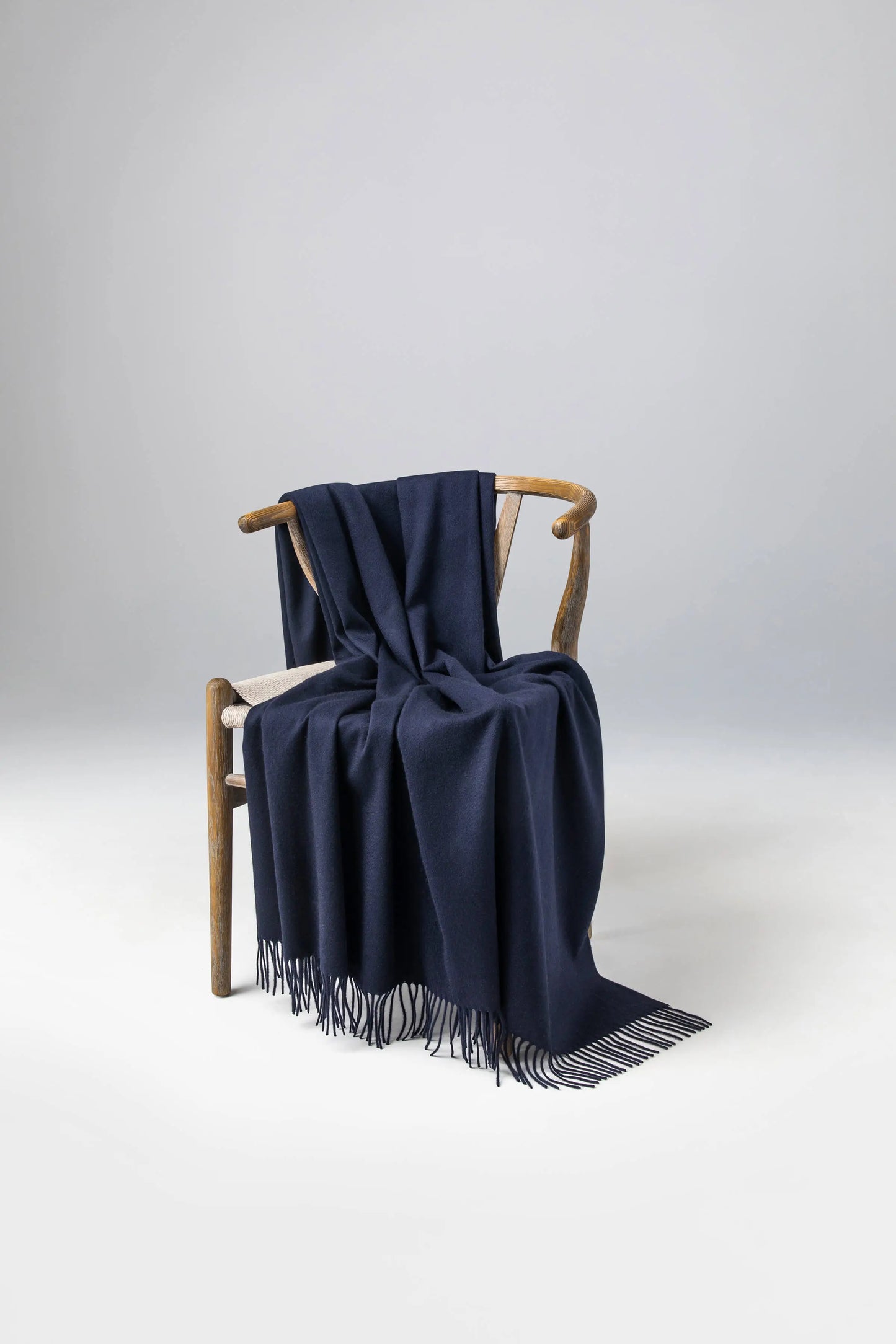 2025 Johnstons of Elgin Interiors Collection  Dark Navy Cashmere Throw on a wooden chair   WA000055SD7330ONE