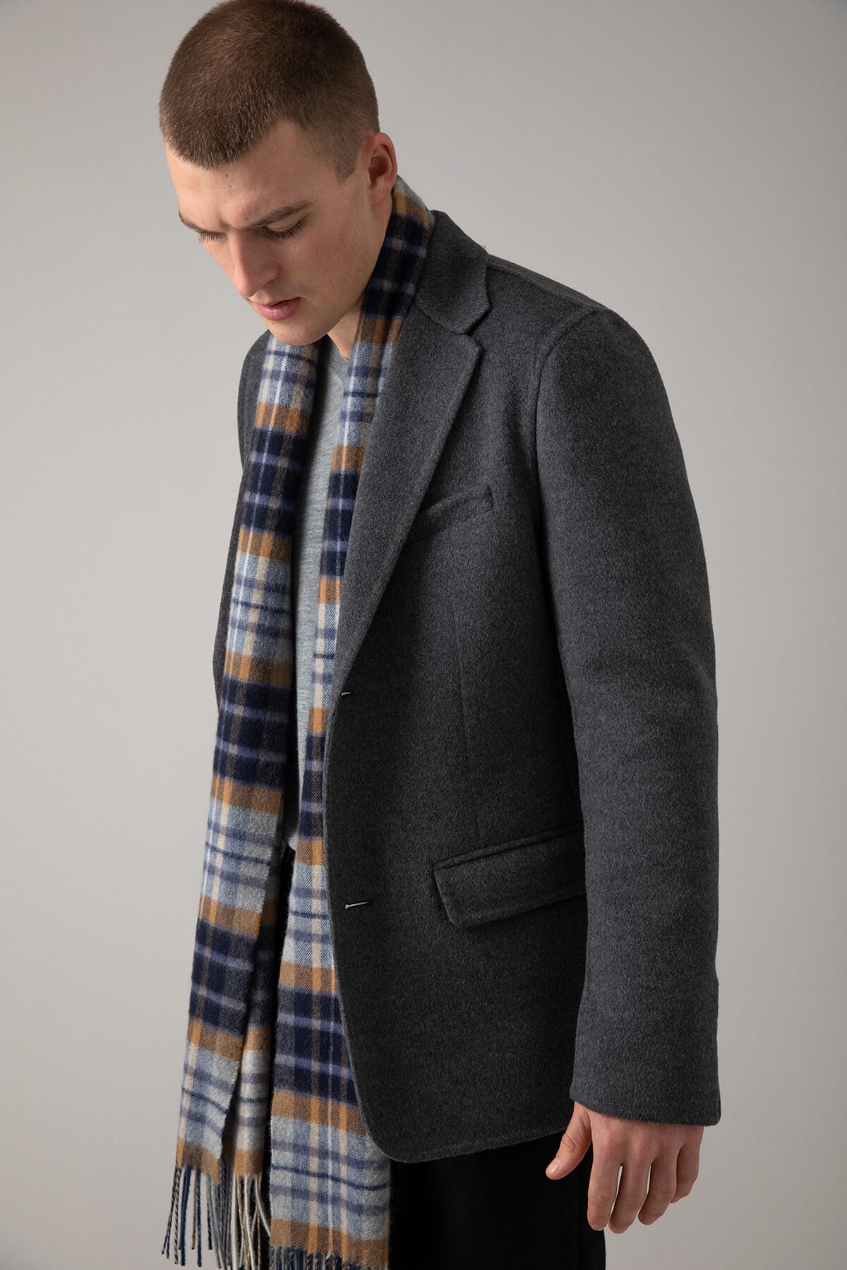 Model wearing Johnstons of Elgin House Check Oversized Tartan Cashmere Scarf on a grey background WA000057RU6933ONE