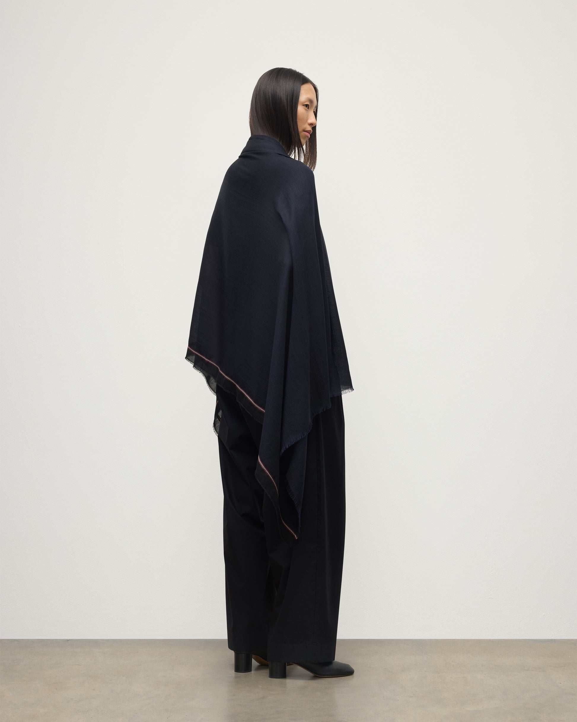 FEMALE MODEL WEARS JOHNSTONS OF ELGIN IVES CHEVRON BORDER SCARF NAVY 100% CASHMERE DRAPED OVER HER SHOULDERS OVER A NAVY CASHMERE SWEATER   WA002446RU7699ONE