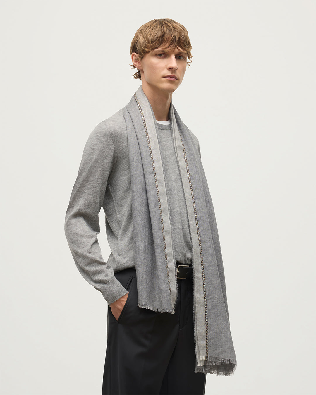 MALE MODEL WEARS JOHNSTON OF ELGIN IVES CHEVRON BORDER SCARF 100% CASHMERE OVER A GREY SUPERFINE CASHMERE SWEATER WA002446RU7700ONE