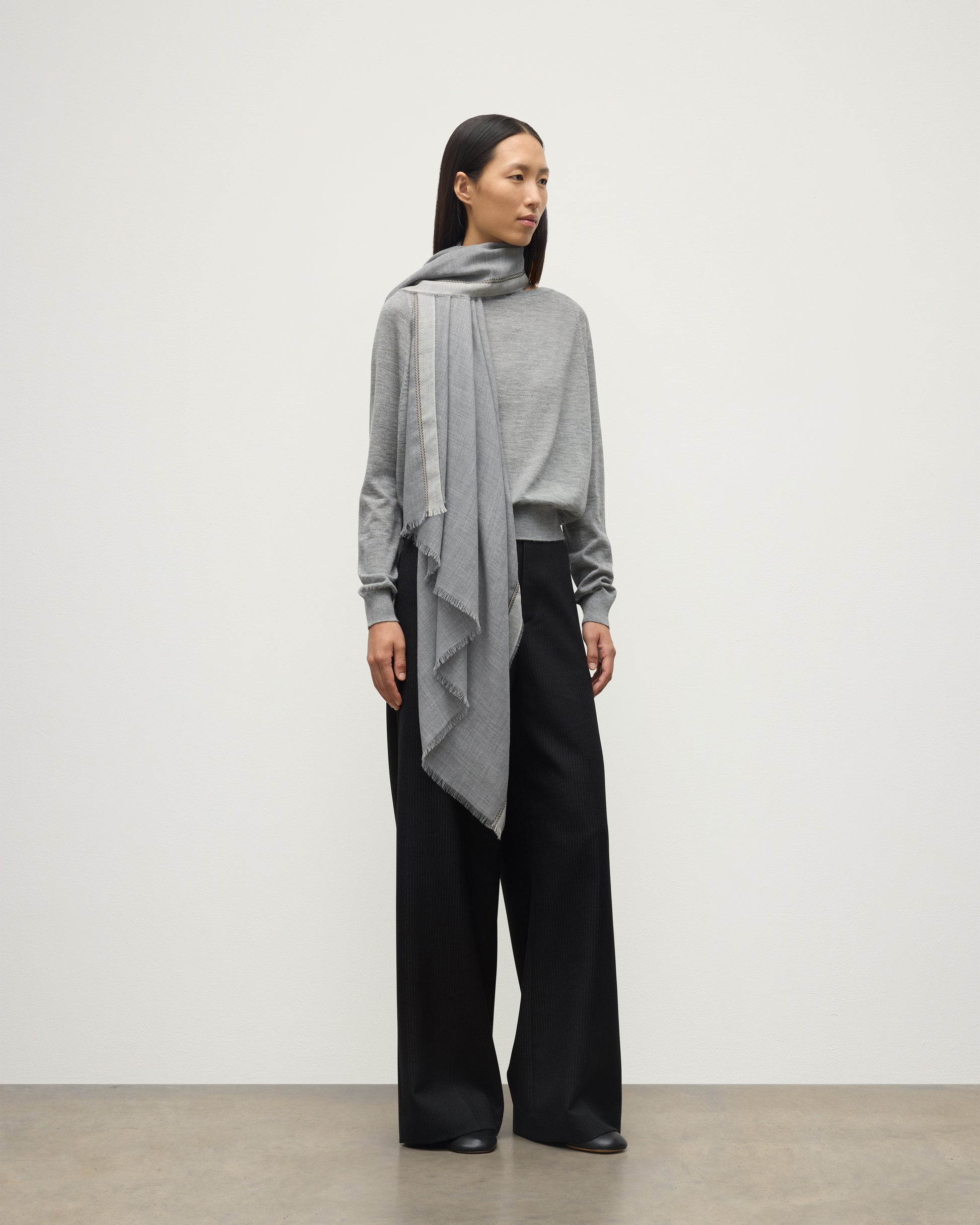 MODEL WEARS JOHNSTON OF ELGIN IVES CHEVRON BORDER SCARF 100% CASHMERE OVER A LIGHT GREY CASHMERE SWEATER WA002446RU7700ONE