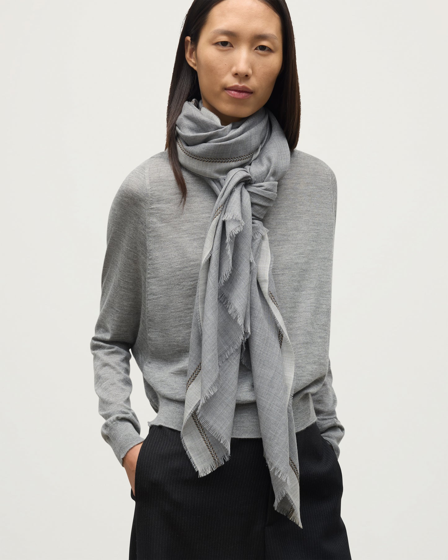 MODEL WEARS JOHNSTON OF ELGIN IVES CHEVRON BORDER SCARF 100% CASHMERE OVER A LIGHT GREY CASHMERE SWEATER WA002446RU7700ONE