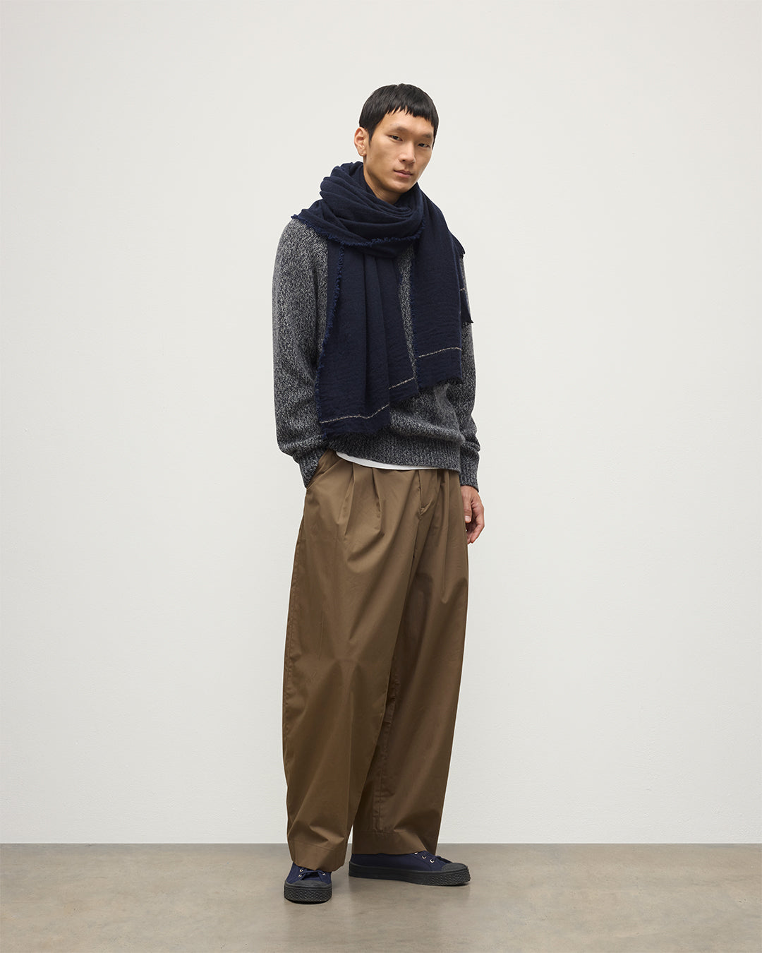 MALE MODEL WEARING JOHNSTONS OF ELGIN USAN SEMI PLAIN SCARF NAVY 100% CASHMERE WITH NAVY MARL CASHMERE SWEATER AND BROWN TROUSERS WA002550RU7720ONE