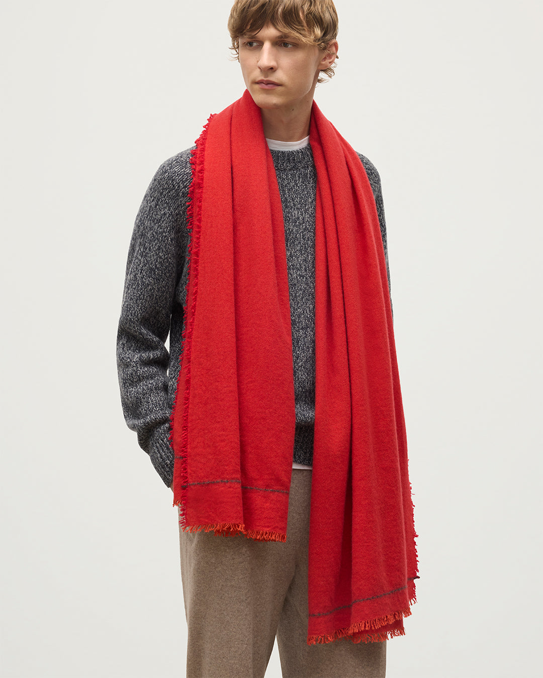 MALE MODEL WEARING JOHNSTONS OF ELGIN USAN SEMI PLAIN SCARF RED 100% CASHMERE WITH NAVY MARL CASHMERE SWEATER, AND BROWN TROUSERS WA002550RU7721ONE