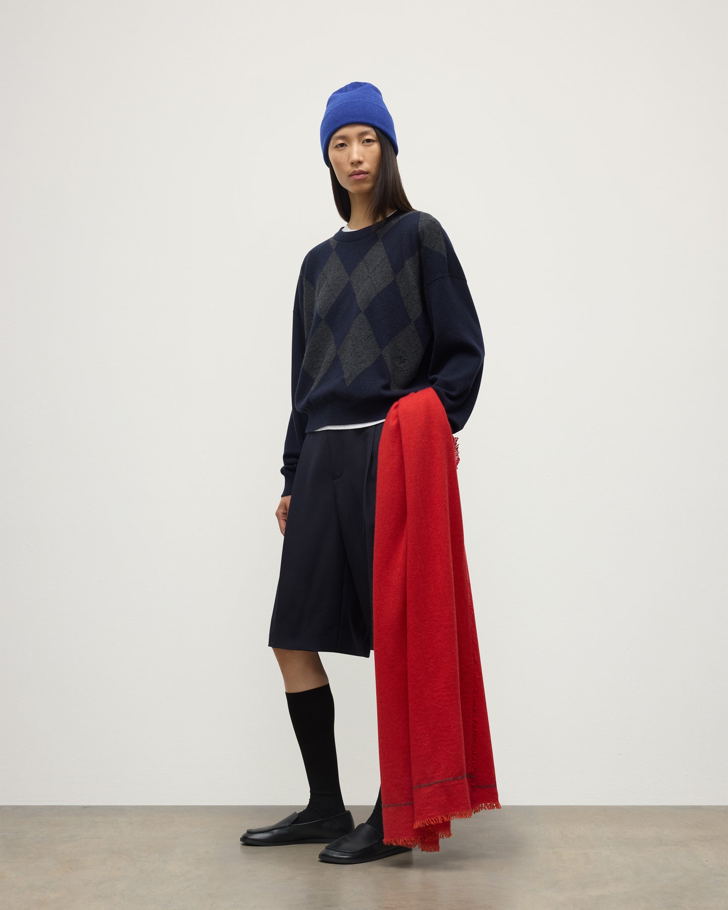 FEMALE MODEL WEARING JOHNSTONS OF ELGIN USAN SEMI PLAIN SCARF RED 100% CASHMERE WITH CLAN ARGYLL CASHMERE SWEATER, KILT AND BRAEMAR BLUE BEANIE WA002550RU7721ONE