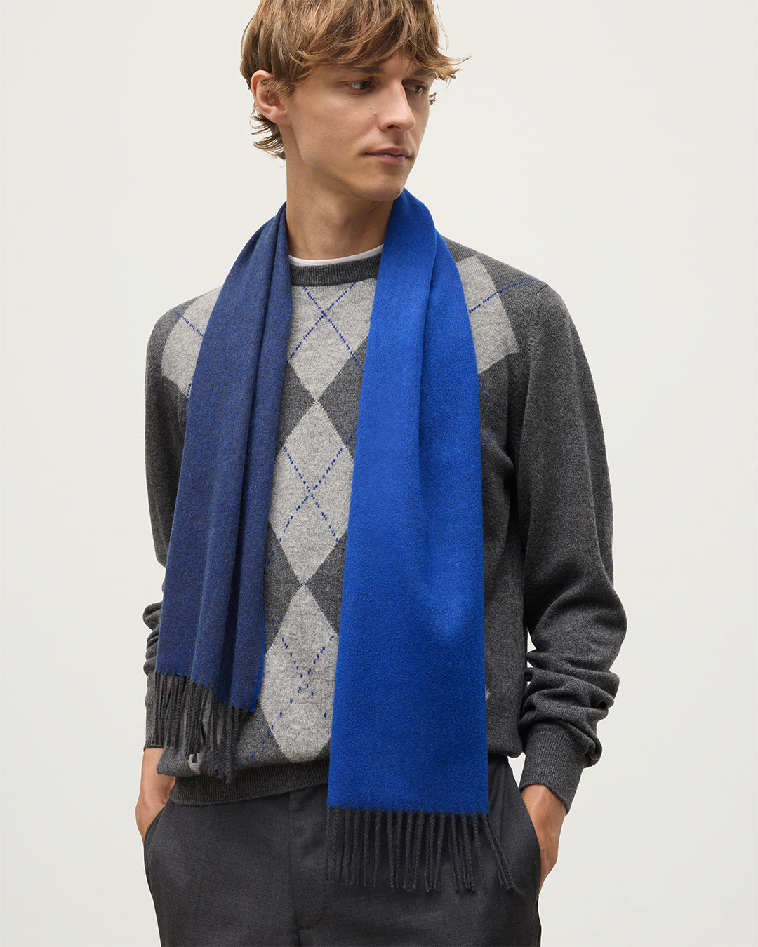 MALE MODEL WEARS JOHNSTONS OF ELGIN BLUE BARD SCARF 100% CASHMERE OVER A GREY ARGYLL SWEATER  WA002560RU7727ONE