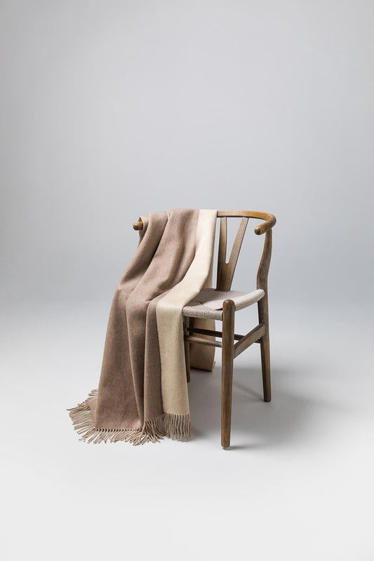 Johnstons of Elgin Reversible Pure Cashmere Throw in Light Brown & Light Grey draped over a wooden chair on a white background WA000013RU5594ONE