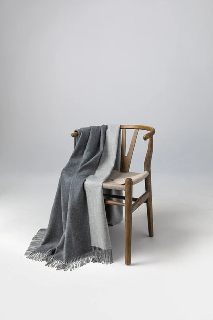 Johnstons of Elgin 2024 Blanket Collection Mid Grey & Silver Plain Reversible Cashmere Throw on a wooden chair WA000013RU7274ONE