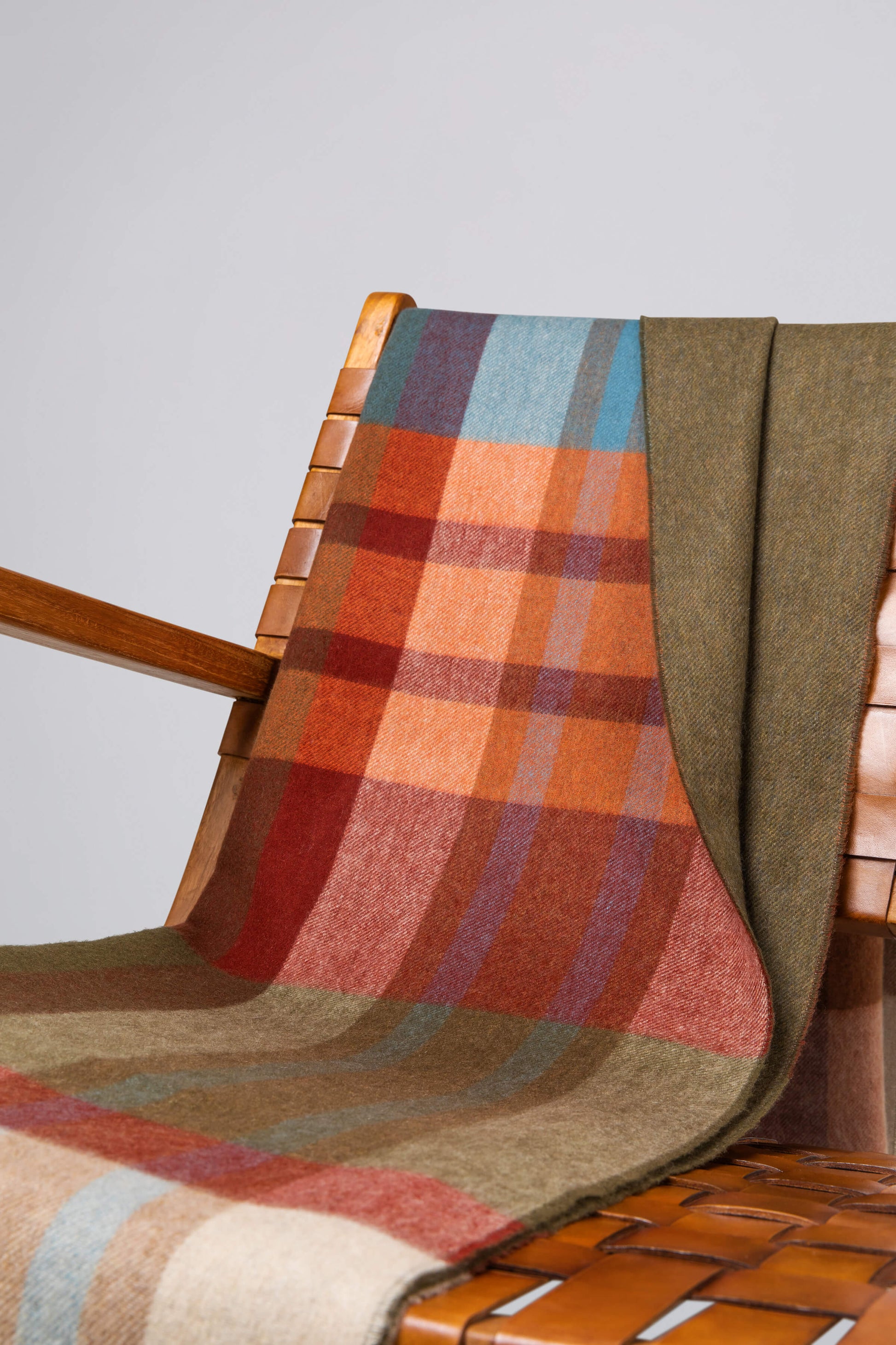 Plaid blanket draped over a wooden chair with a plain background WA000013RU7286ONE