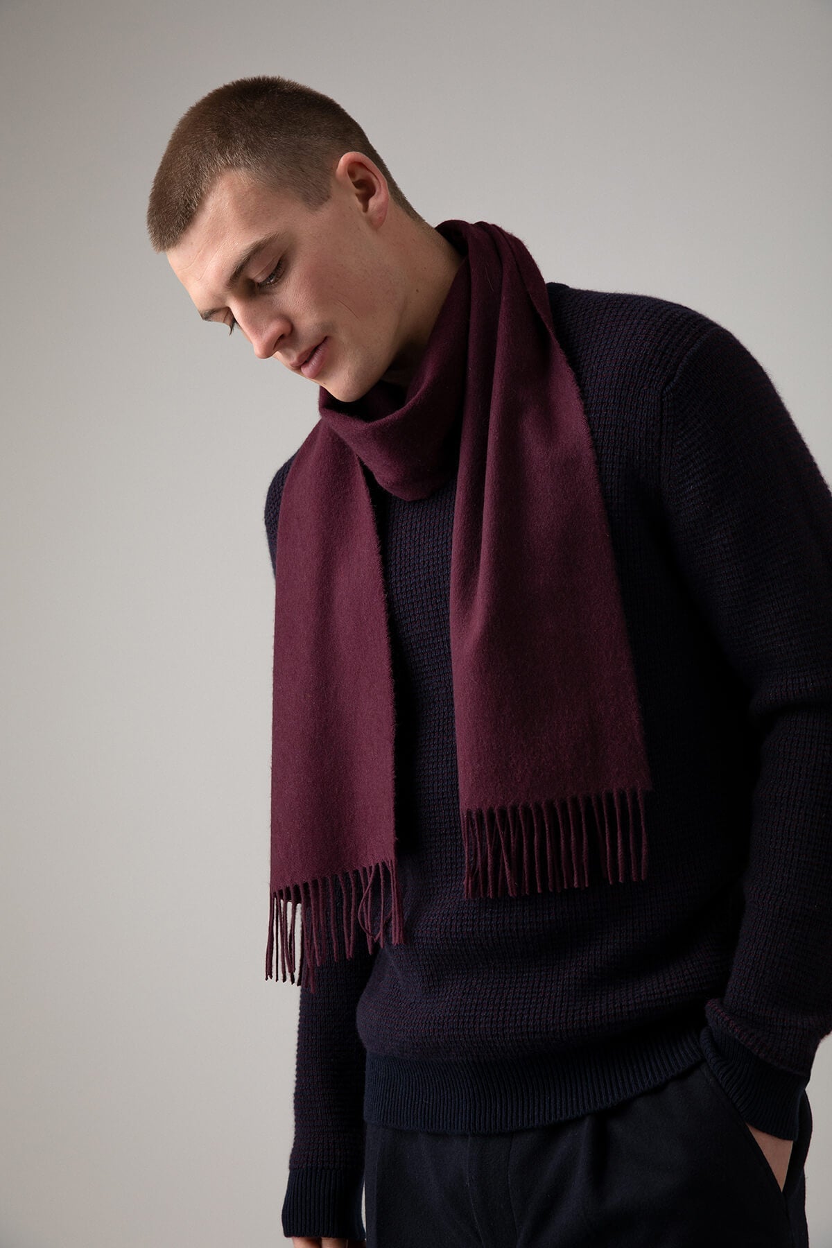 Model wearing Johnstons of Elgin Cashmere Scarf in Bramble on a grey background WA000016SE7388ONE