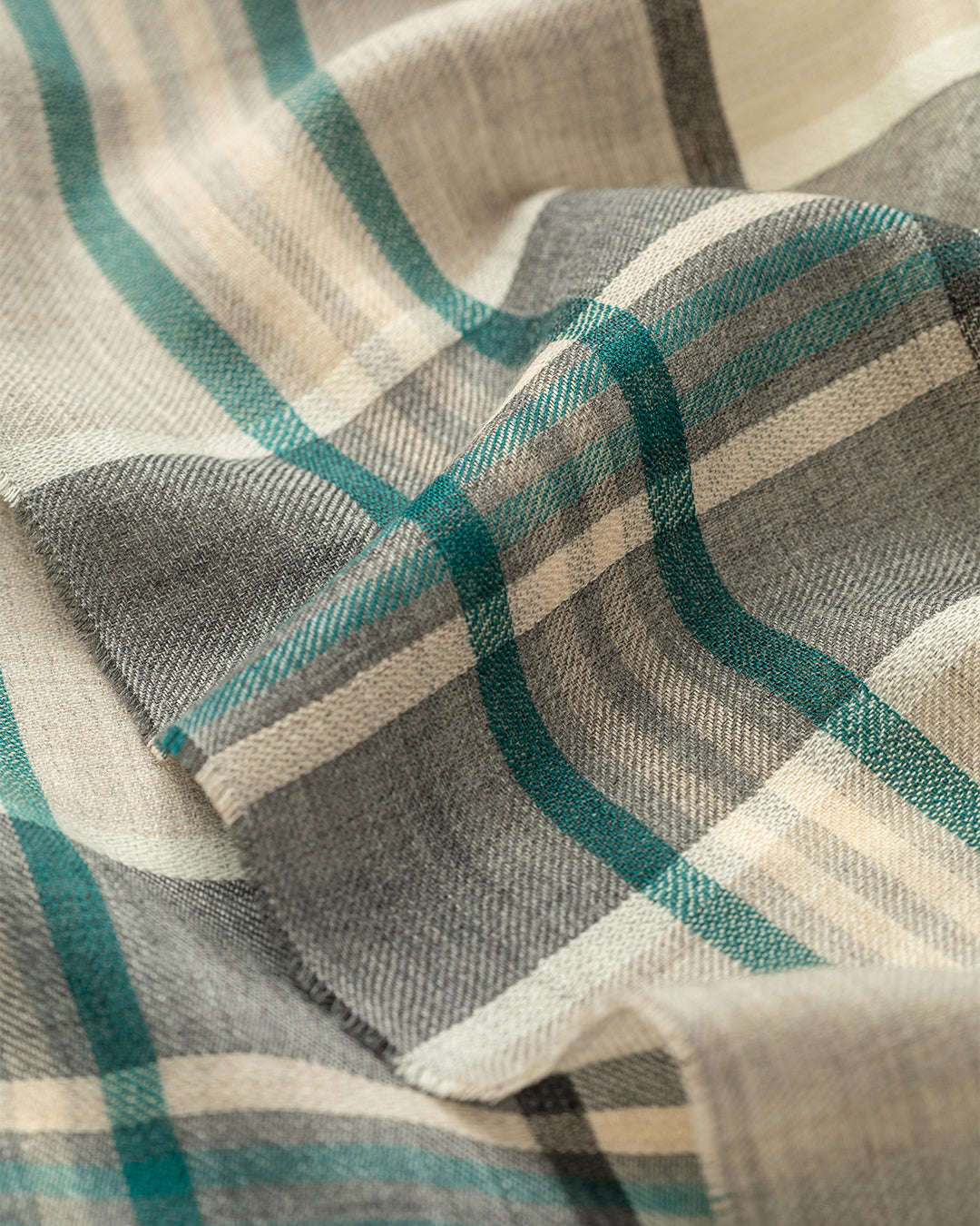 Close-up of a plaid fabric with green, gray, and beige colors. JOHNSTONS OF ELGIN ORTON CRAMMED TARTAN SCARF NEUTRAL 100% CASHMERE WA002447RU7702ONE