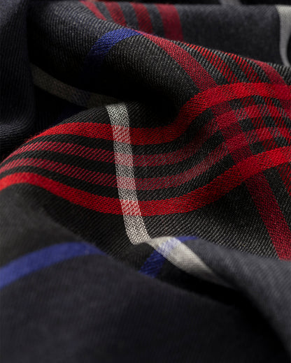 Close-up of a plaid fabric with red, black, and blue stripes. JOHNSTONS OF ELGIN ORTON CRAMMED TARTAN SCARF NAVY 100% CASHMERE WA002447RU7703ONE