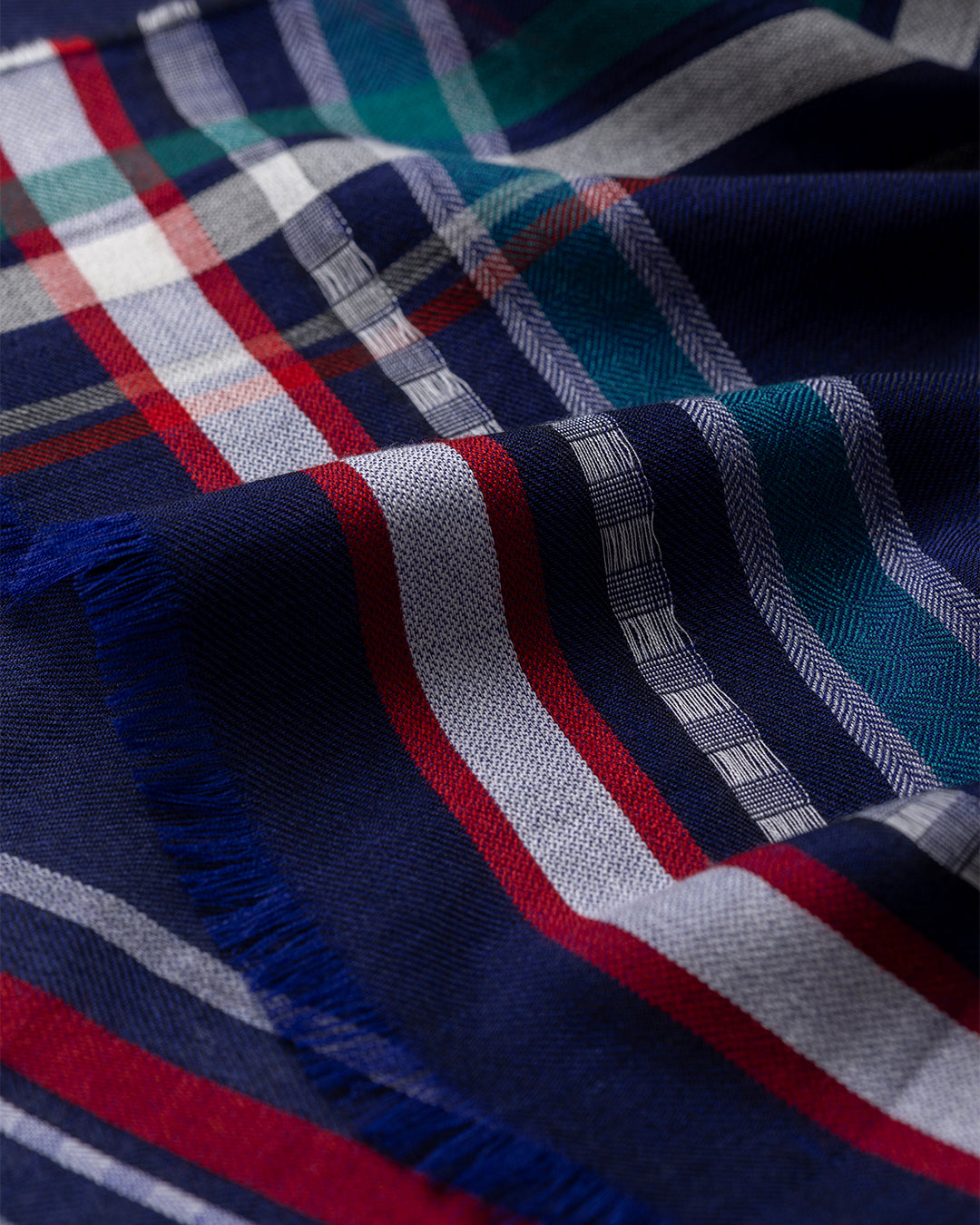 Close-up of a plaid fabric with blue, red, and white colors. JOHNSTONS OF ELGIN HELMINA CRAMMED DETAIL BORDER SCARF NAVY 100% CASHMERE WA002459RU7705ONE
