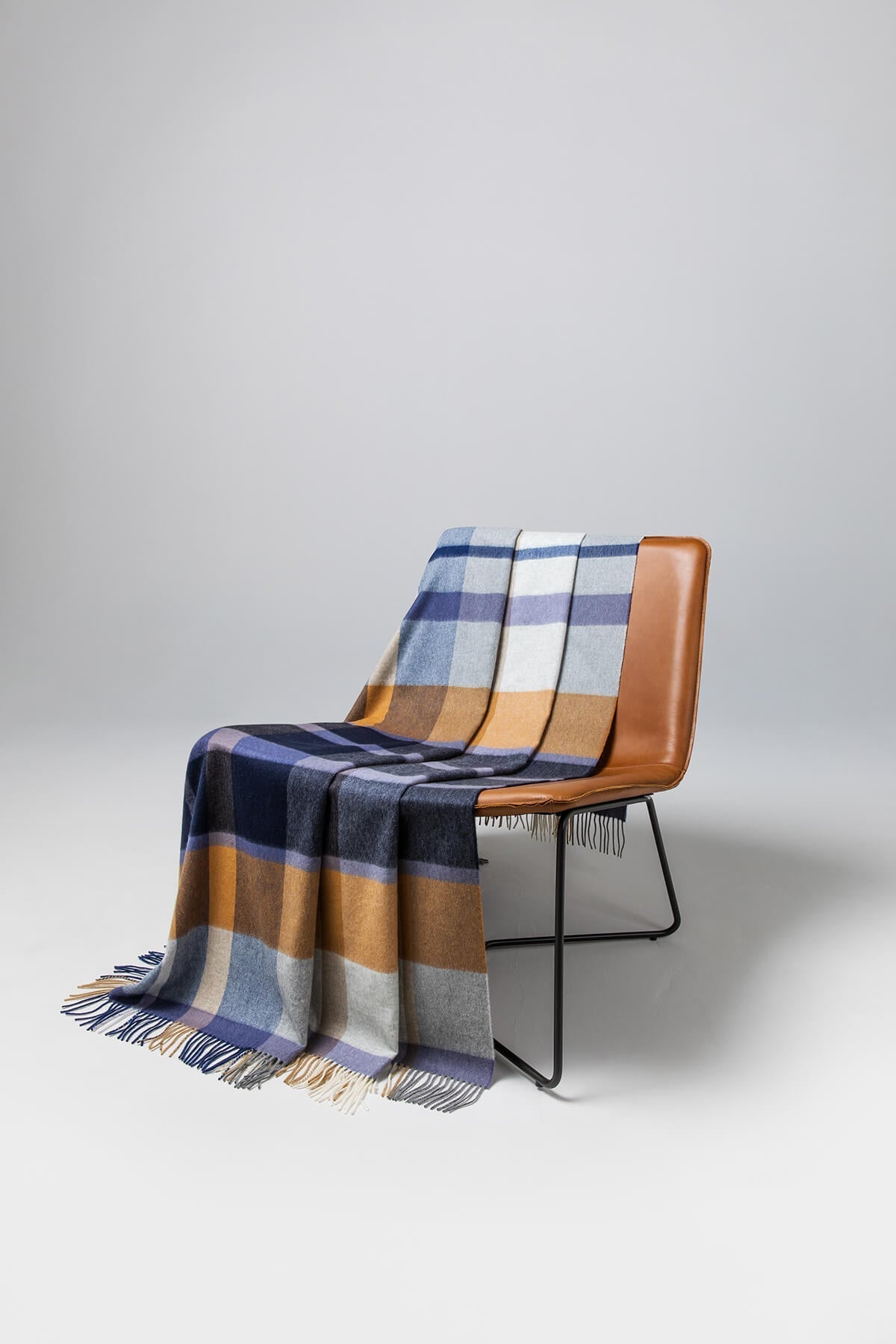 Johnstons of Elgin’s House Check Cashmere Throw on brown chair on a grey background WA000055RU7060ONE