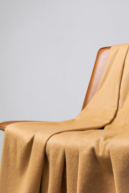 Johnstons of Elgin’s Camel Cashmere Throw on brown chair on a grey background WA000055SB4142