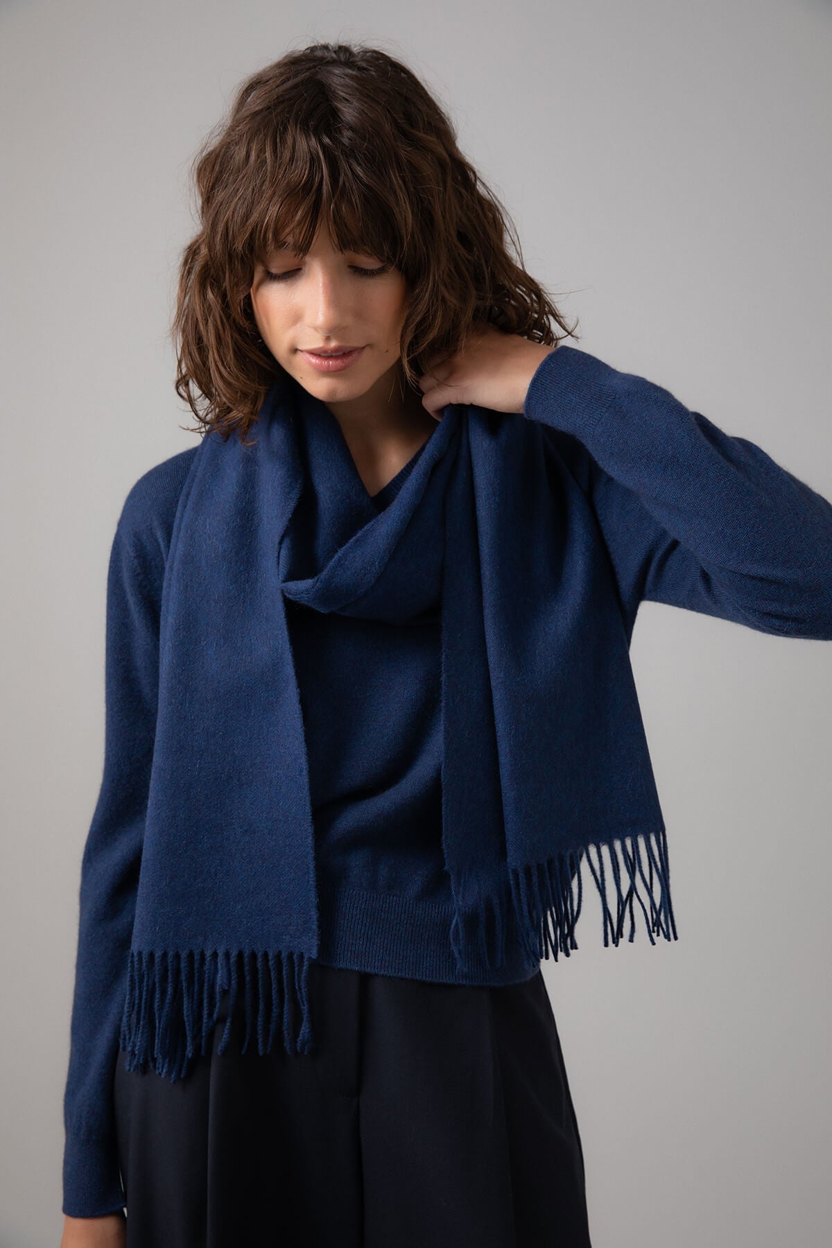 Model wearing Johnstons of Elgin Oversized Cashmere Scarf in Ocean on a grey background WA000057HD7244ONE