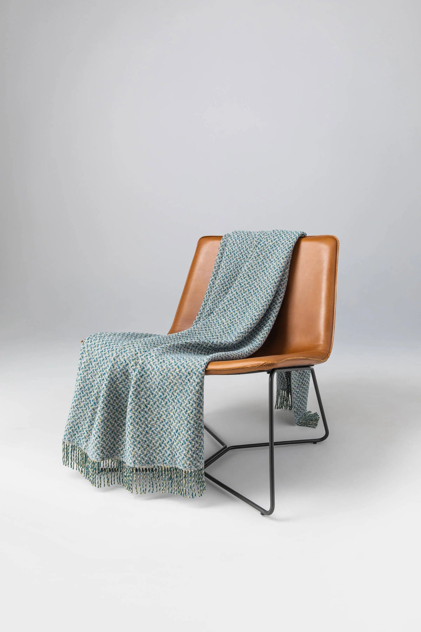 Johnstons of Elgin 2024 Blanket Collection Cool Neutral Tweed Texture Throw on a leather chair WB002458RU7549ONE