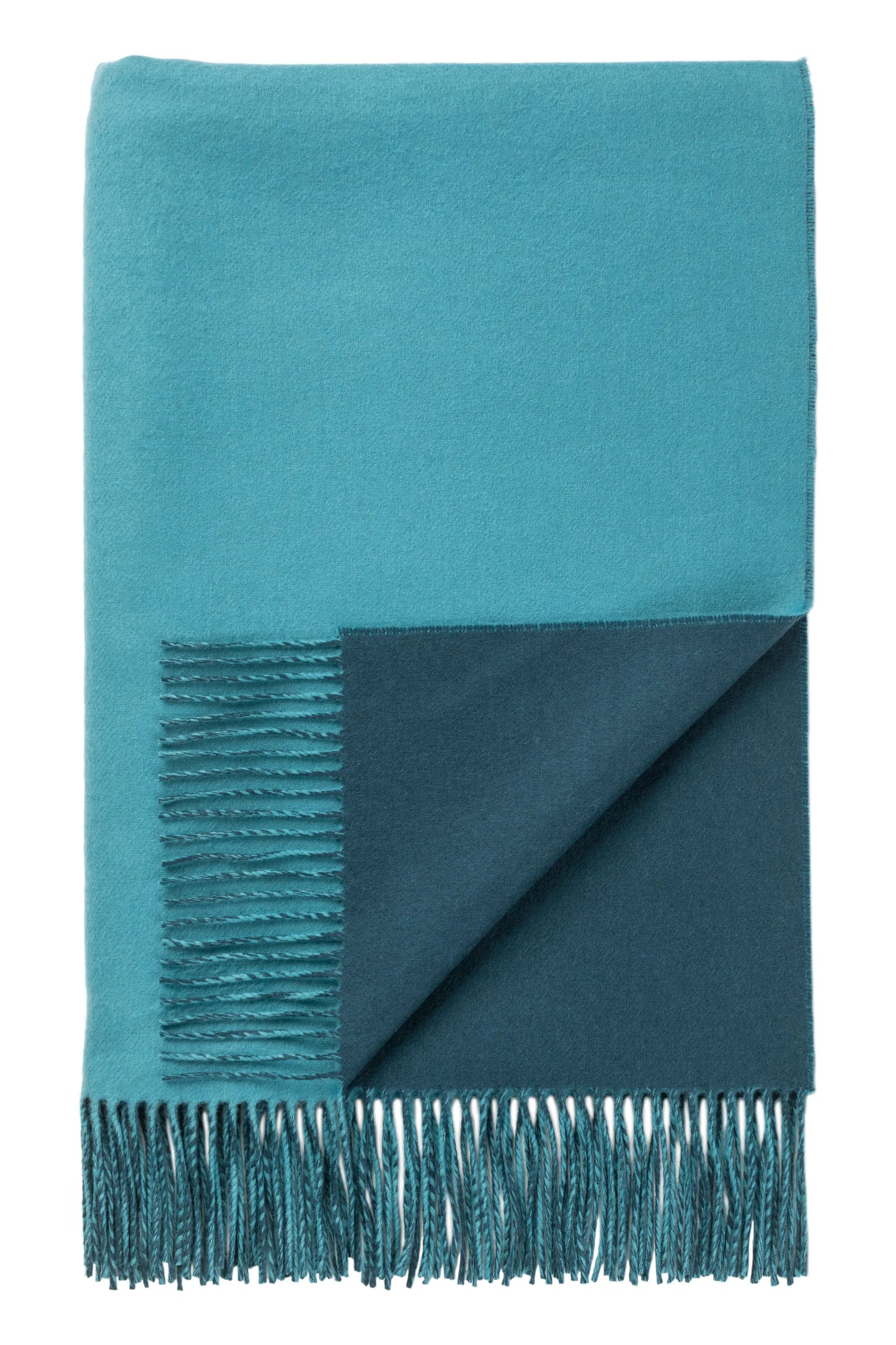 Johnstons of Elgin’s Teal Blue & Ocean Reversible Merino Blend Throw on brown chair on a grey background WB000751RU7260ONE