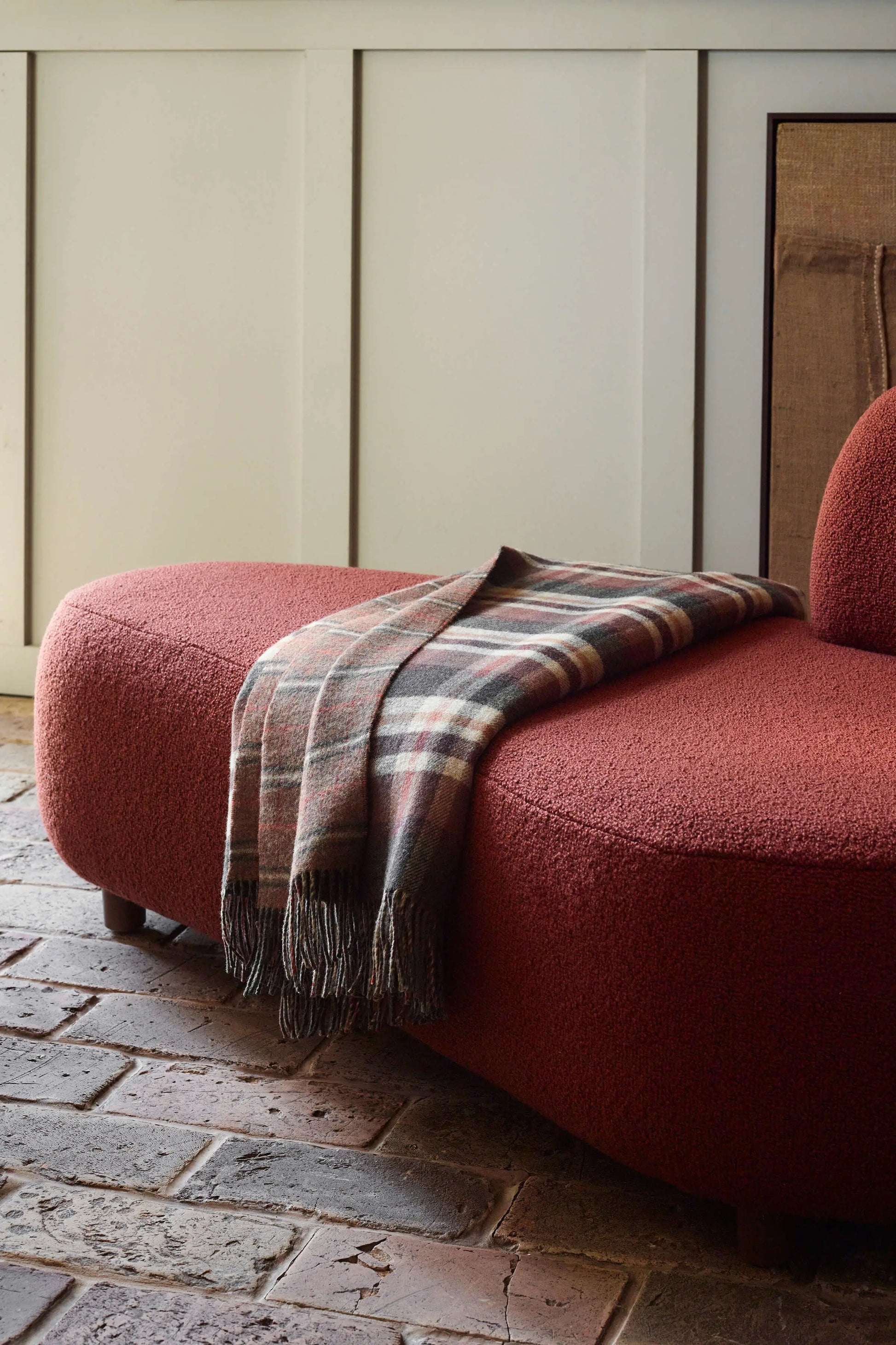 2025 Johnstons of Elgin Interiors Collection Block Check & Windowpane check Reversible Lambswool Throw on a rust red wool boucle sofa WD000021RU7413ONE