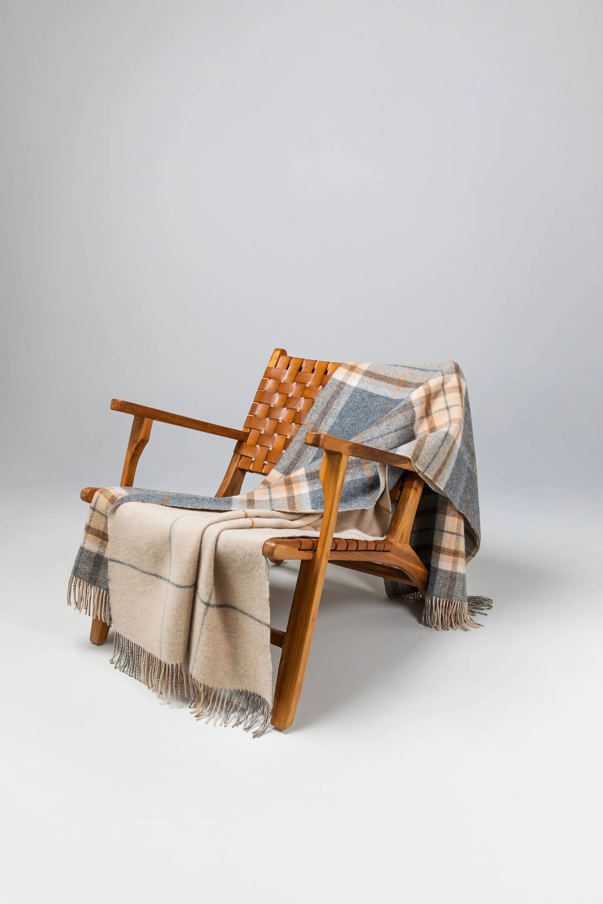 2025 Johnstons of Elgin Interiors Collection Grey & Brown Overcheck Reversible Lambswool Throw on a wooden chair WD000021RU6954ONE