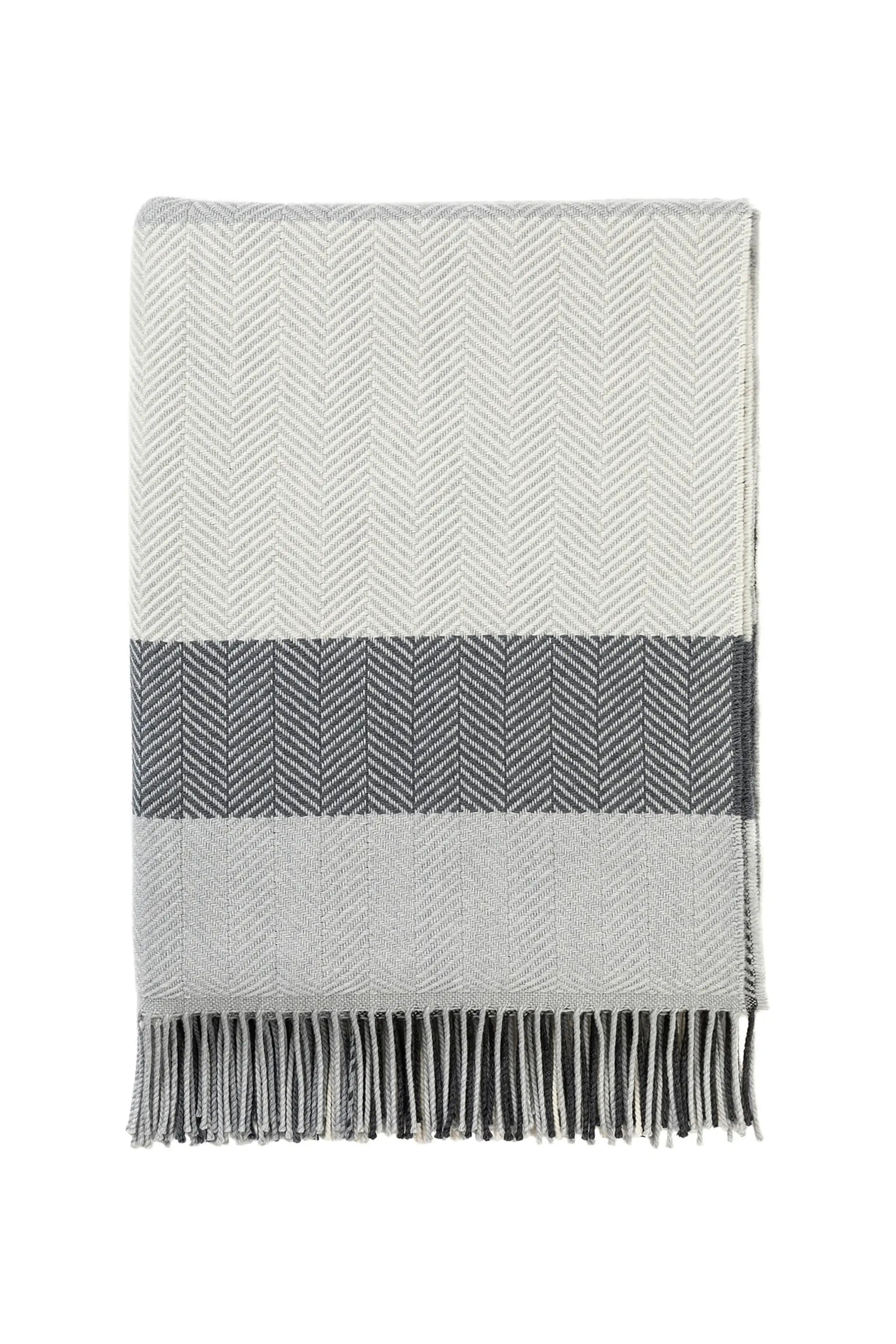 Johnstons of Elgin’s Grey & White Lofty Check Merino Throw on brown chair on a grey background WD001221RU6980ONE