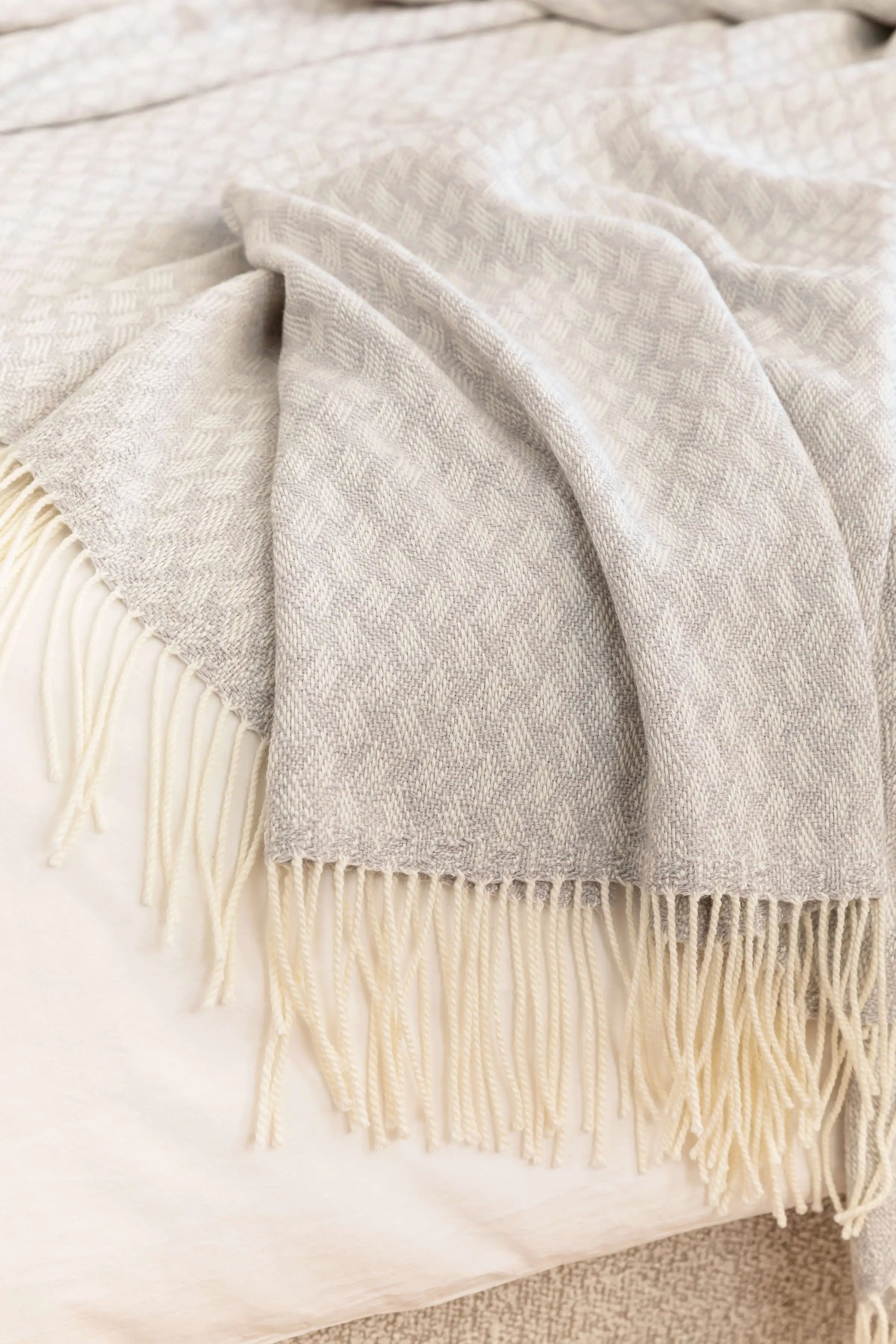 Johnstons of Elgin’s Lattice Weave Merino Bed Throw in Silver & White on bed in neutral bedroom WD001243RU7269ONE