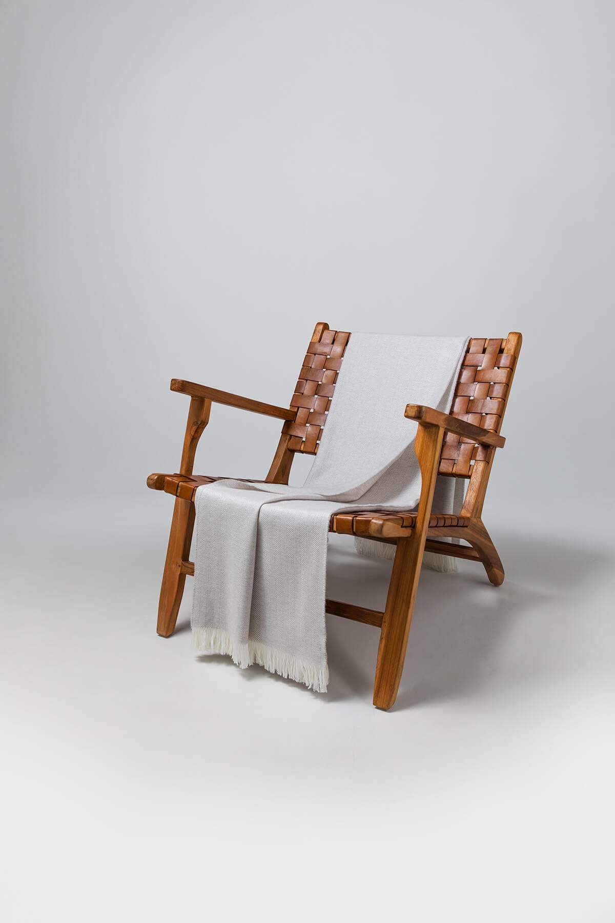 Johnstons of Elgin's Silver Birch & White Herringbone Merino Throw on brown chair on a grey background WD000010RU5831ONE