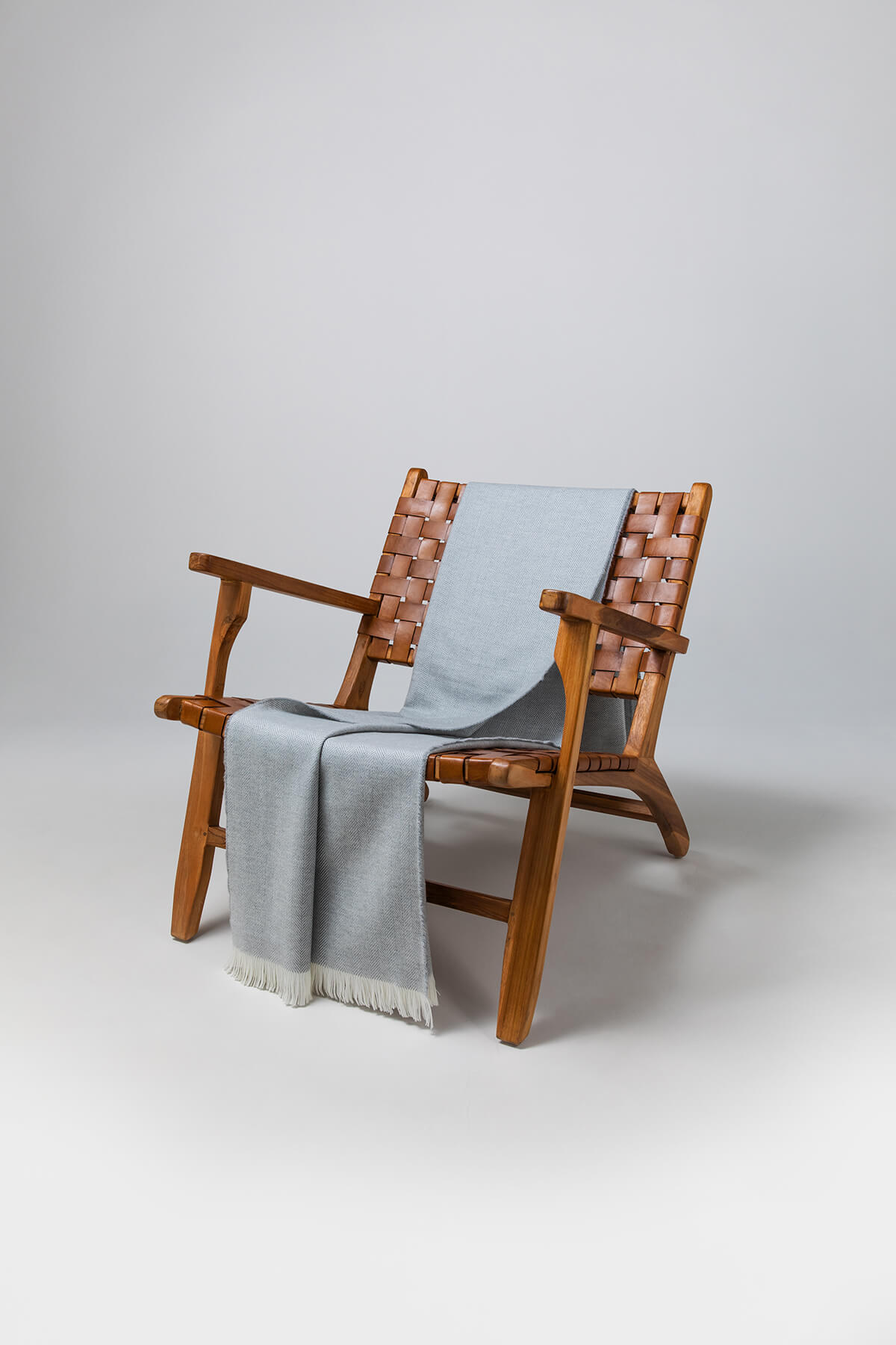 Johnstons of Elgin's Mist & White Herringbone Merino Throw on brown chair on a grey background WD000010RU5834ONE