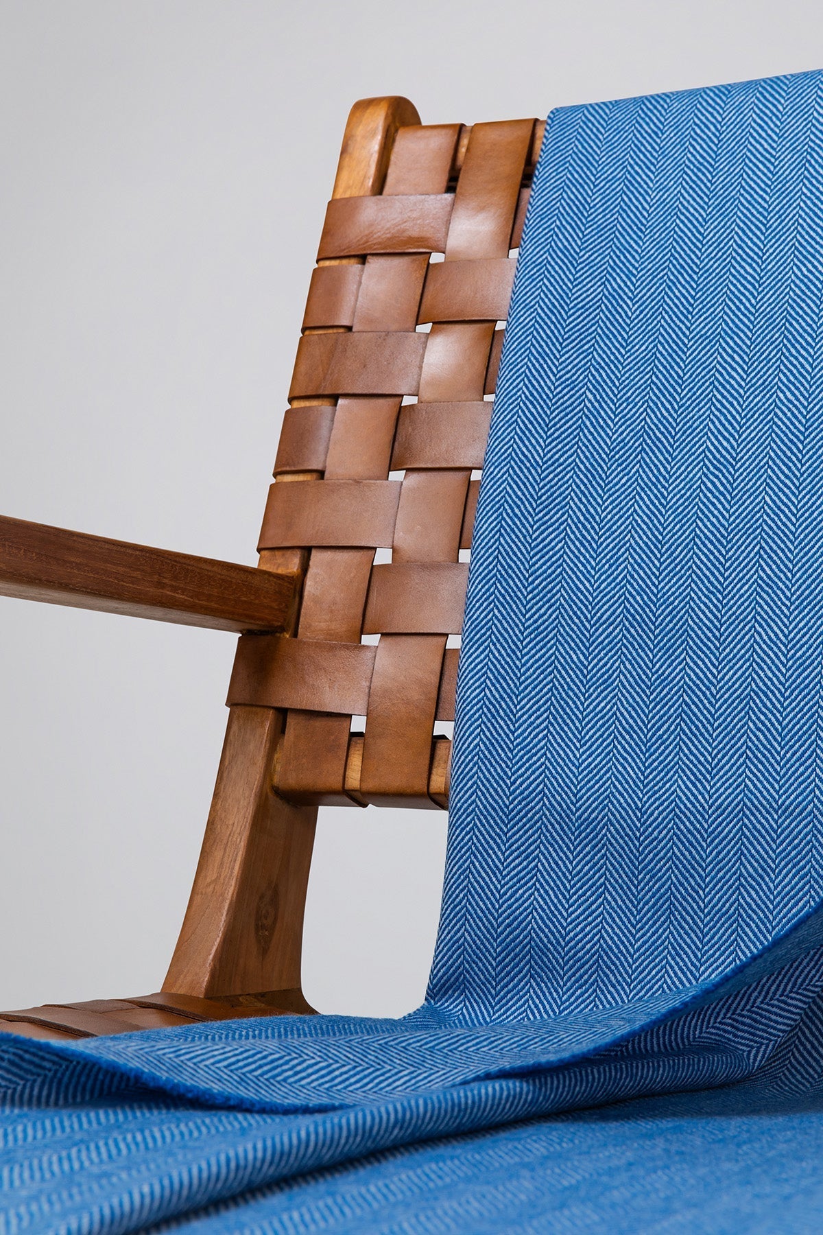 Close Up Johnstons of Elgin's Cobalt & White Herringbone Merino Throw on brown chair on a grey background WD000010RU7261ONE