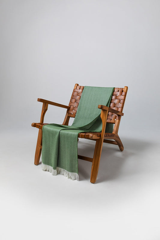 Johnstons of Elgin's Fern & White Herringbone Merino Throw on brown chair on a grey background WD000010RU7262ONE