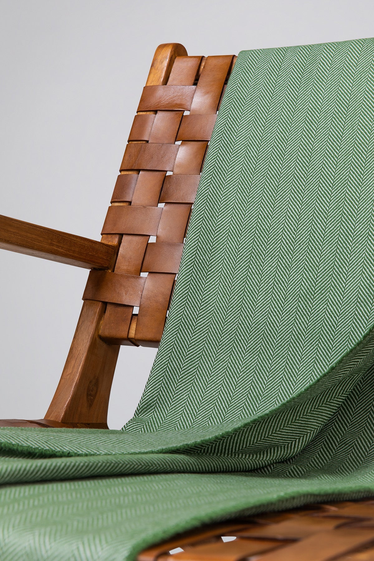 Close Up Johnstons of Elgin's Fern & White Herringbone Merino Throw on brown chair on a grey background WD000010RU7262ONE