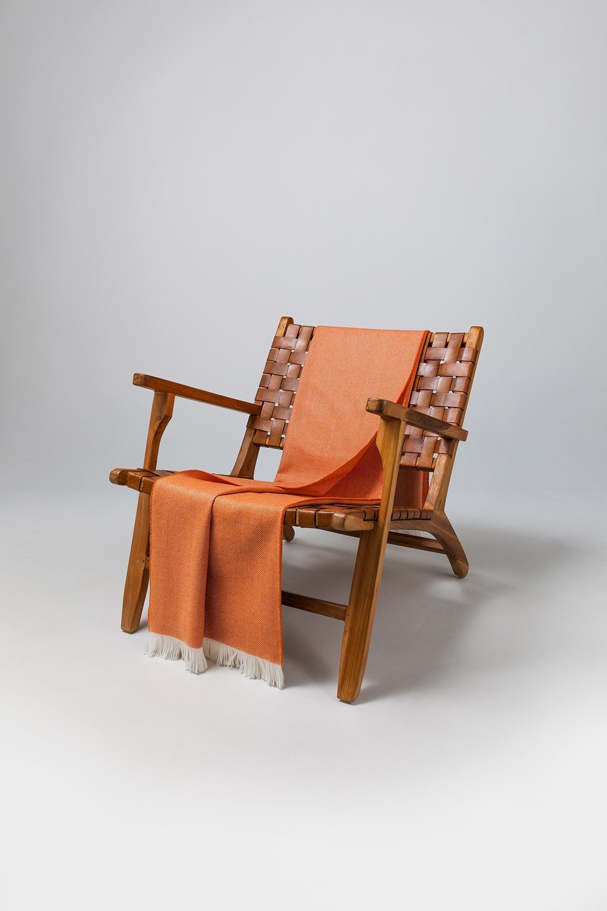 Johnstons of Elgin's Orange & White Herringbone Merino Throw on brown chair on a grey background WD000010RU7266ONE