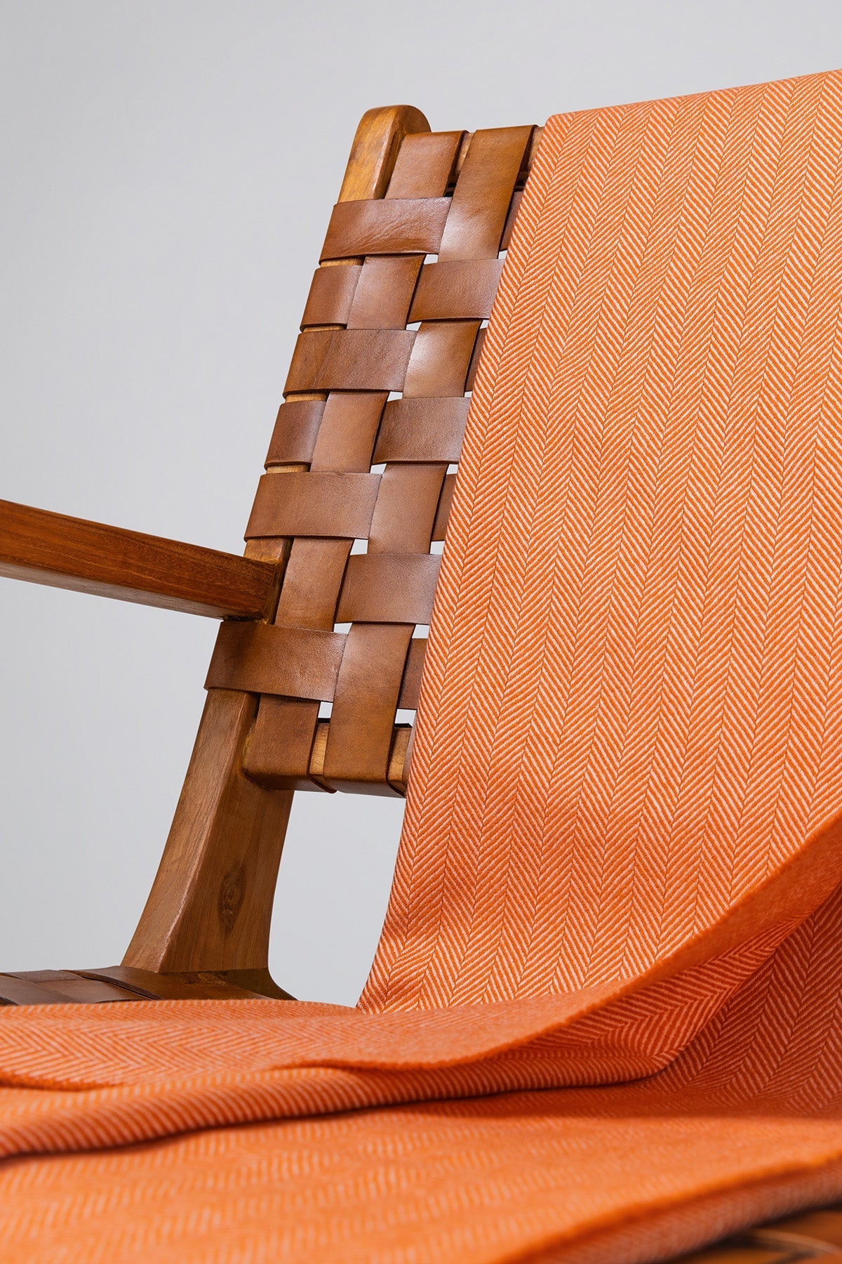 Close up Johnstons of Elgin's Orange & White Herringbone Merino Throw on brown chair on a grey background WD000010RU7266ONE