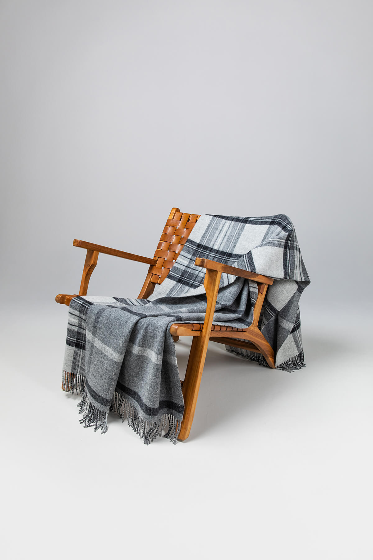 Johnstons of Elgin’s Double Face Grey Stewart & Windowpane Check Lambswool Throw on brown chair on a grey background WD000021RU6624N/A