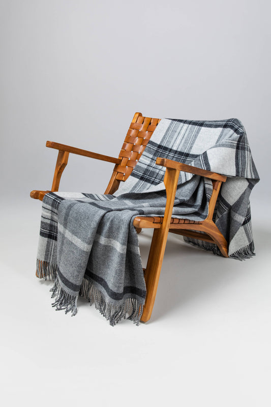 Johnstons of Elgin’s Double Face Grey Stewart & Windowpane Check Lambswool Throw on brown chair on a grey background WD000021RU6624N/A